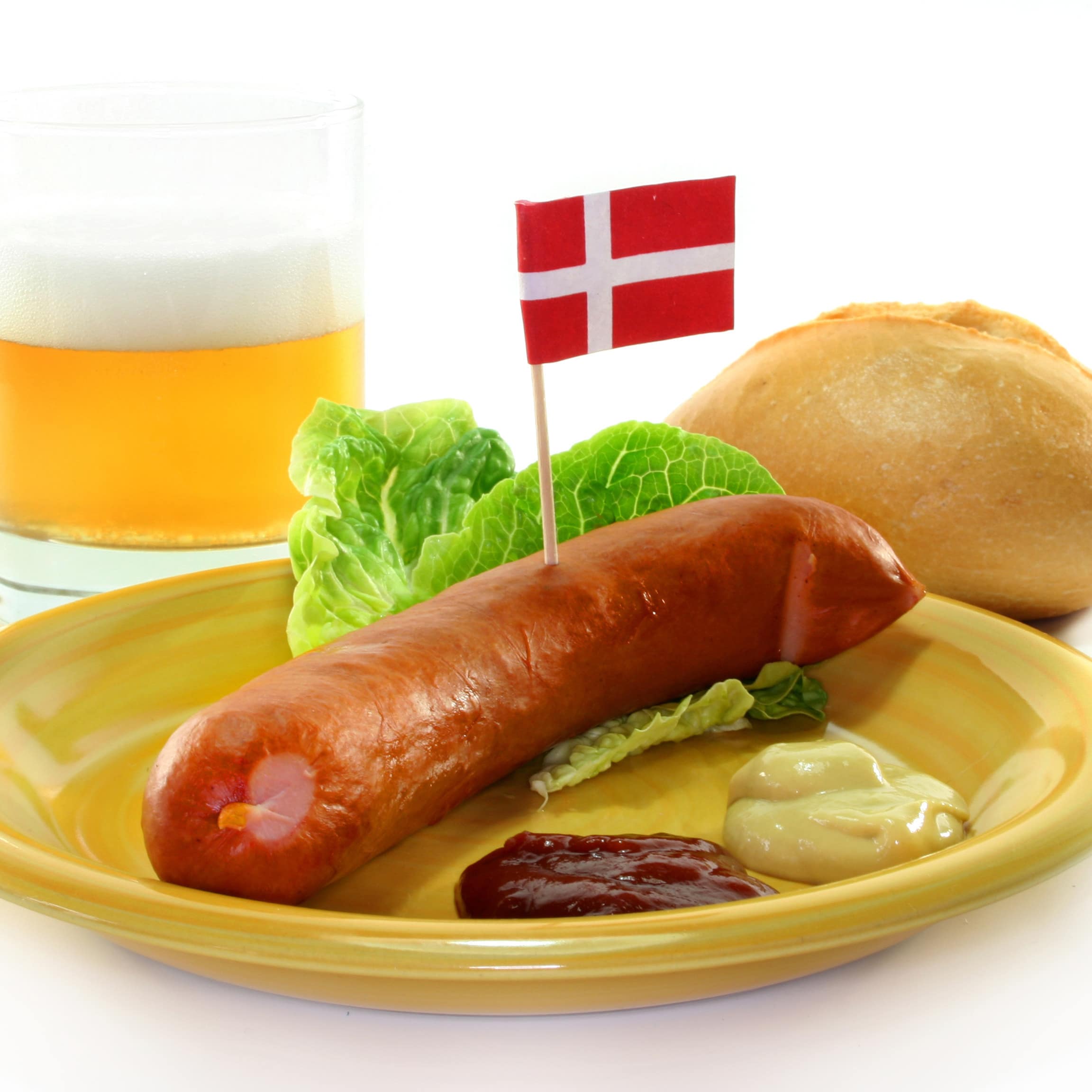 Gelber Teller mit dänischer Wurst, dahinter ein Brötchen und ein Glas Bier.