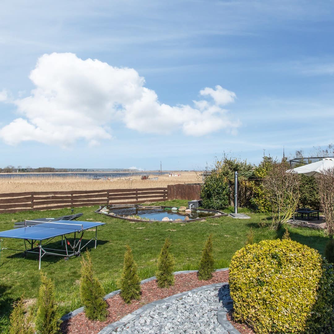 Garten mit Tischtennisplatte, Teich und Sitzgelegenheiten in einer Ferienwohnung in Karlshagen, Blick auf Schilf und Wasser