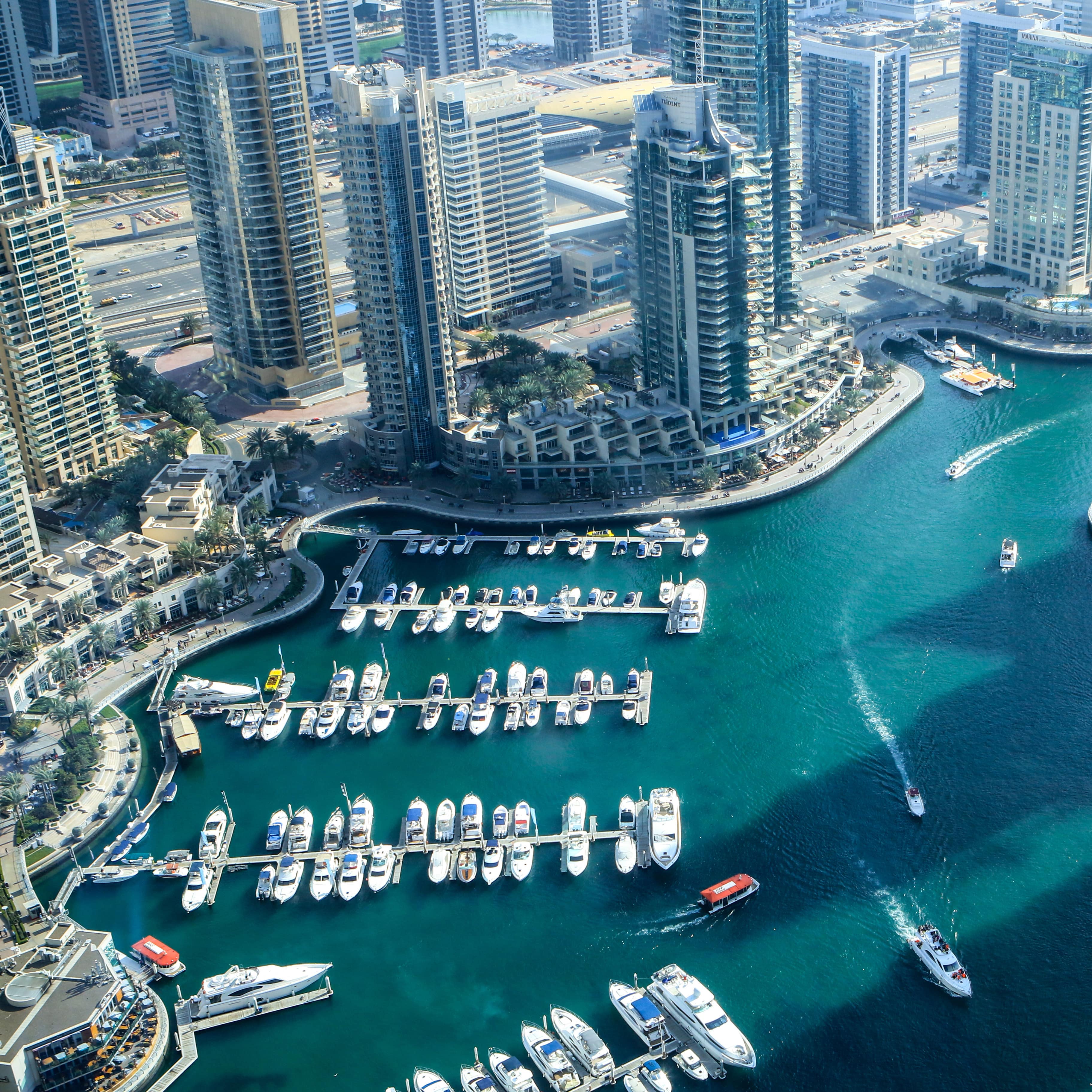 Blick von oben auf das moderne Dubai, eine Marina und das Meer.