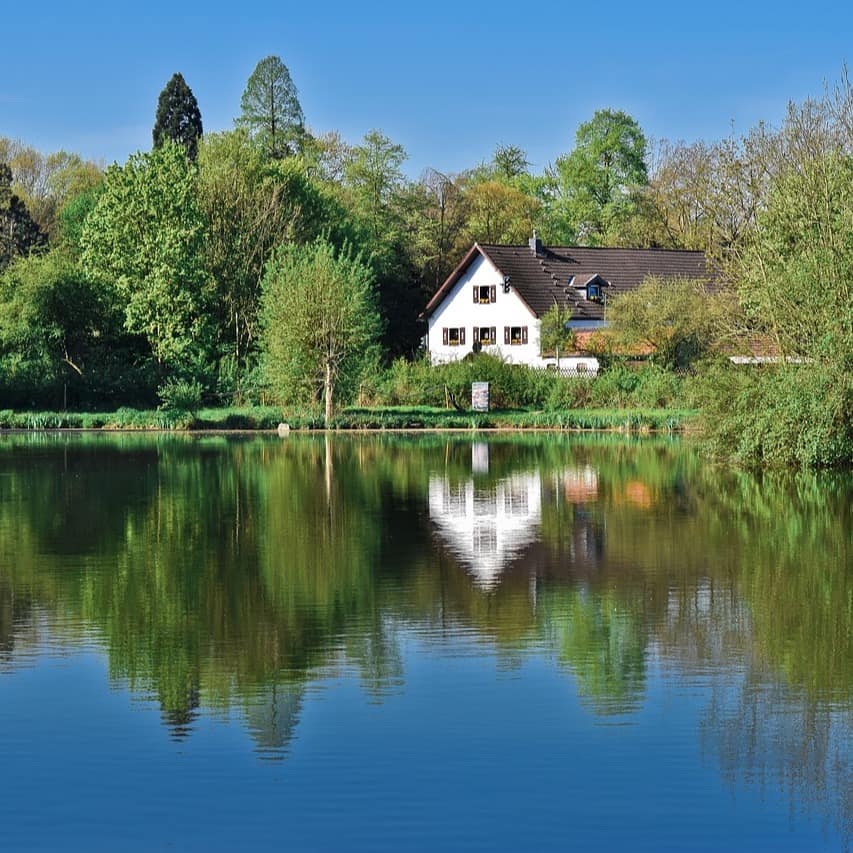 Ein Haus am Ufer eines Sees umgeben von Bäumen