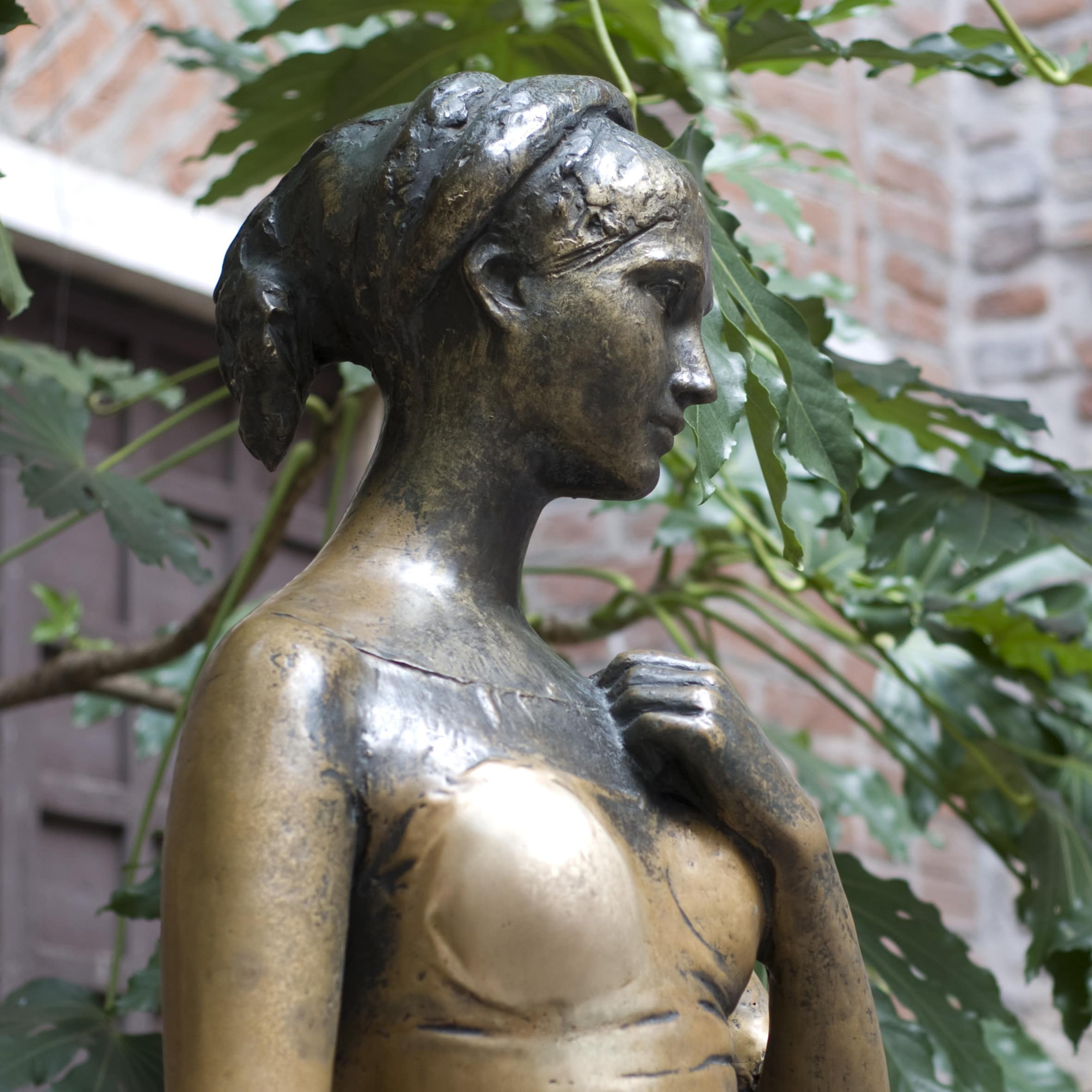 Nahaufnahme von der Julia-Statue in Verona, dahinter ein Baum.