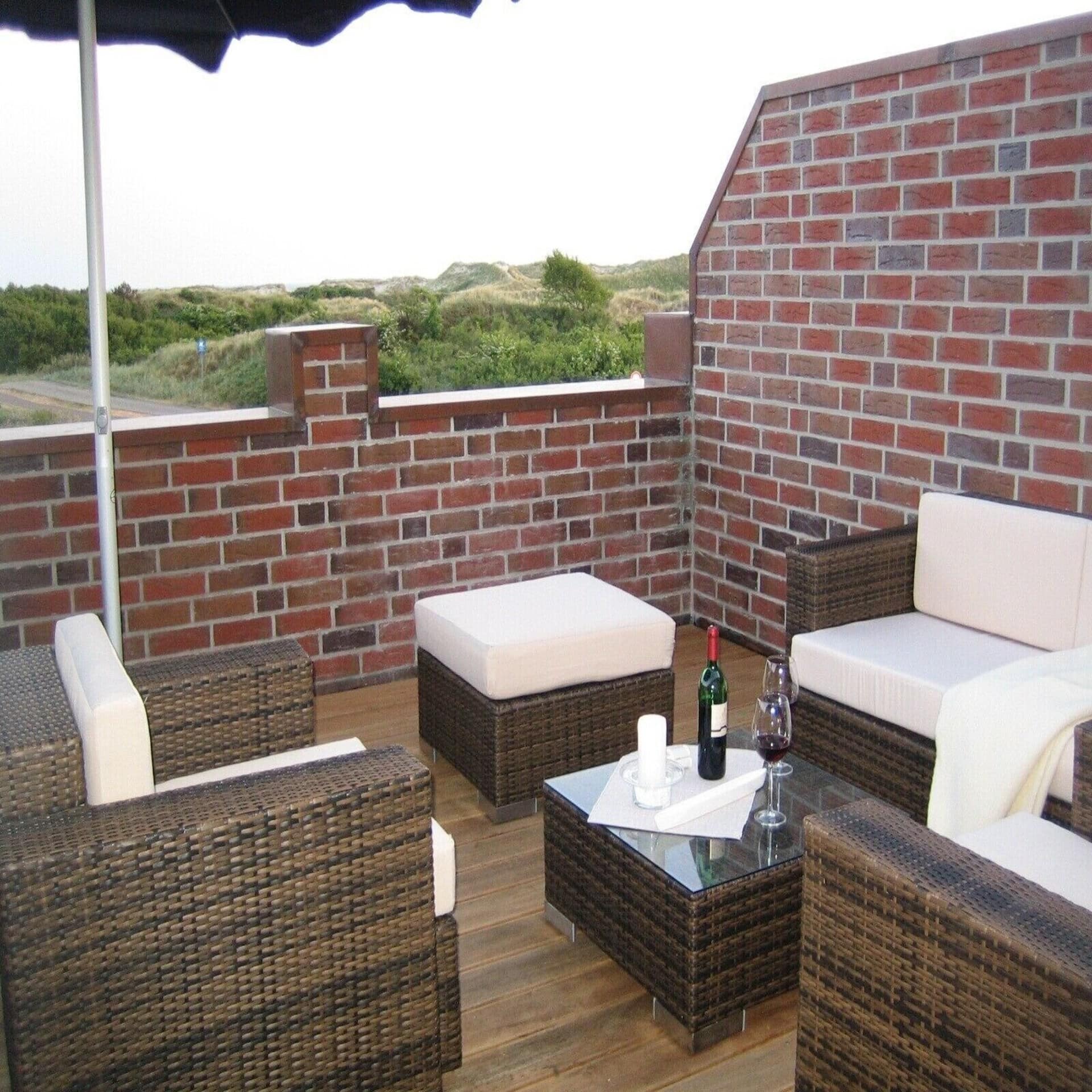 Dachterrasse mit Gartenmöbeln und Blick auf die Dünen. 