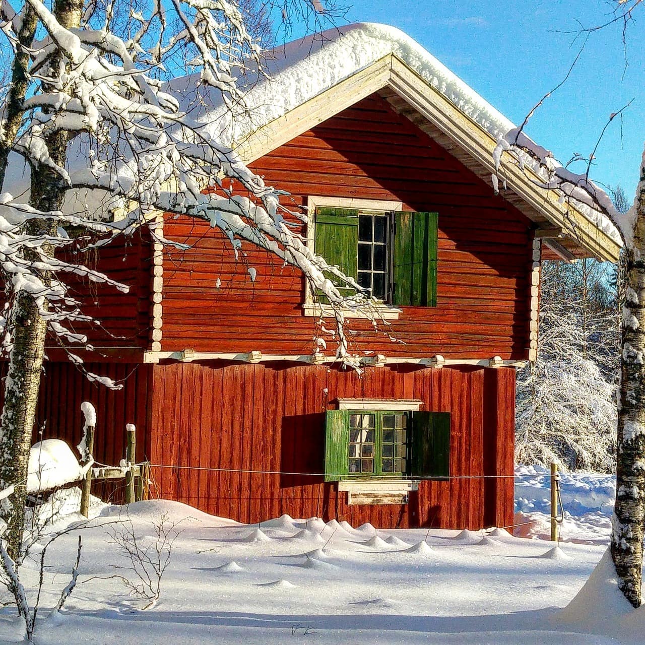 Eine Holzhütte mit grünen Fensterläden in einer verschneiten Landschaft