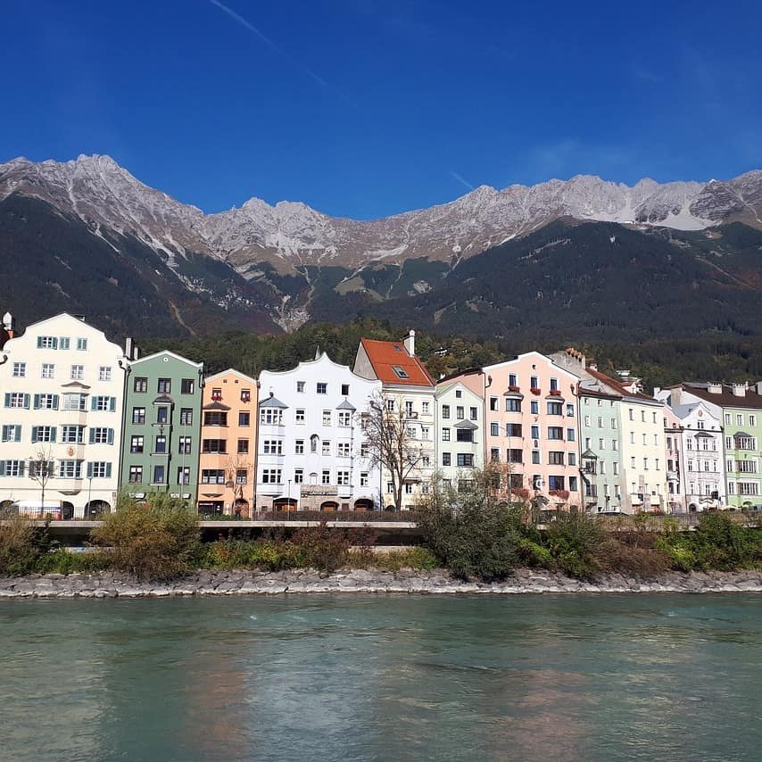 Blick vom Wasser auf die Häuser von Innsbruck mit Bergen im Hintergrund