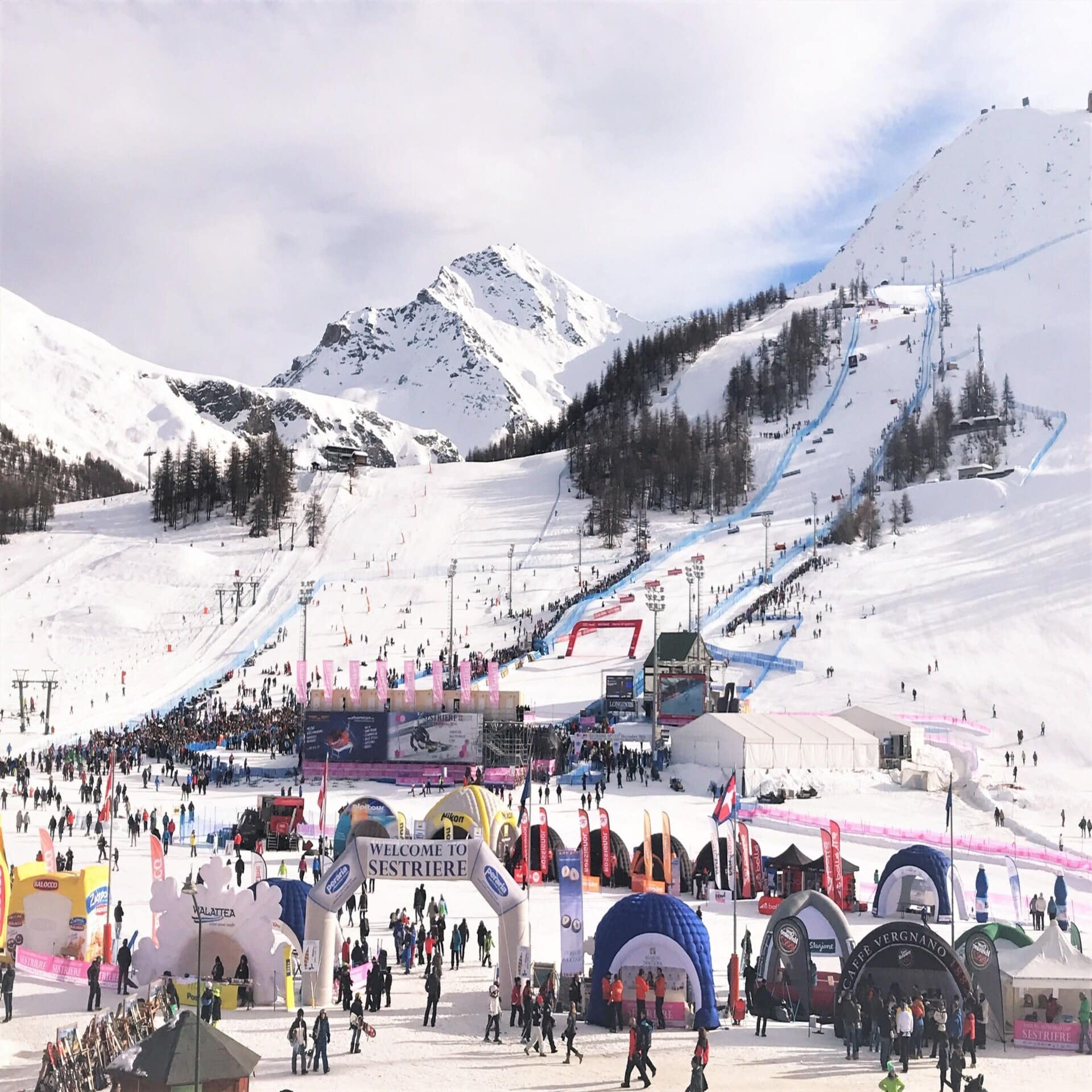 Viele Personen am Eingang des Skigebiets in Sestriere in Italien. Die Sonne scheint.