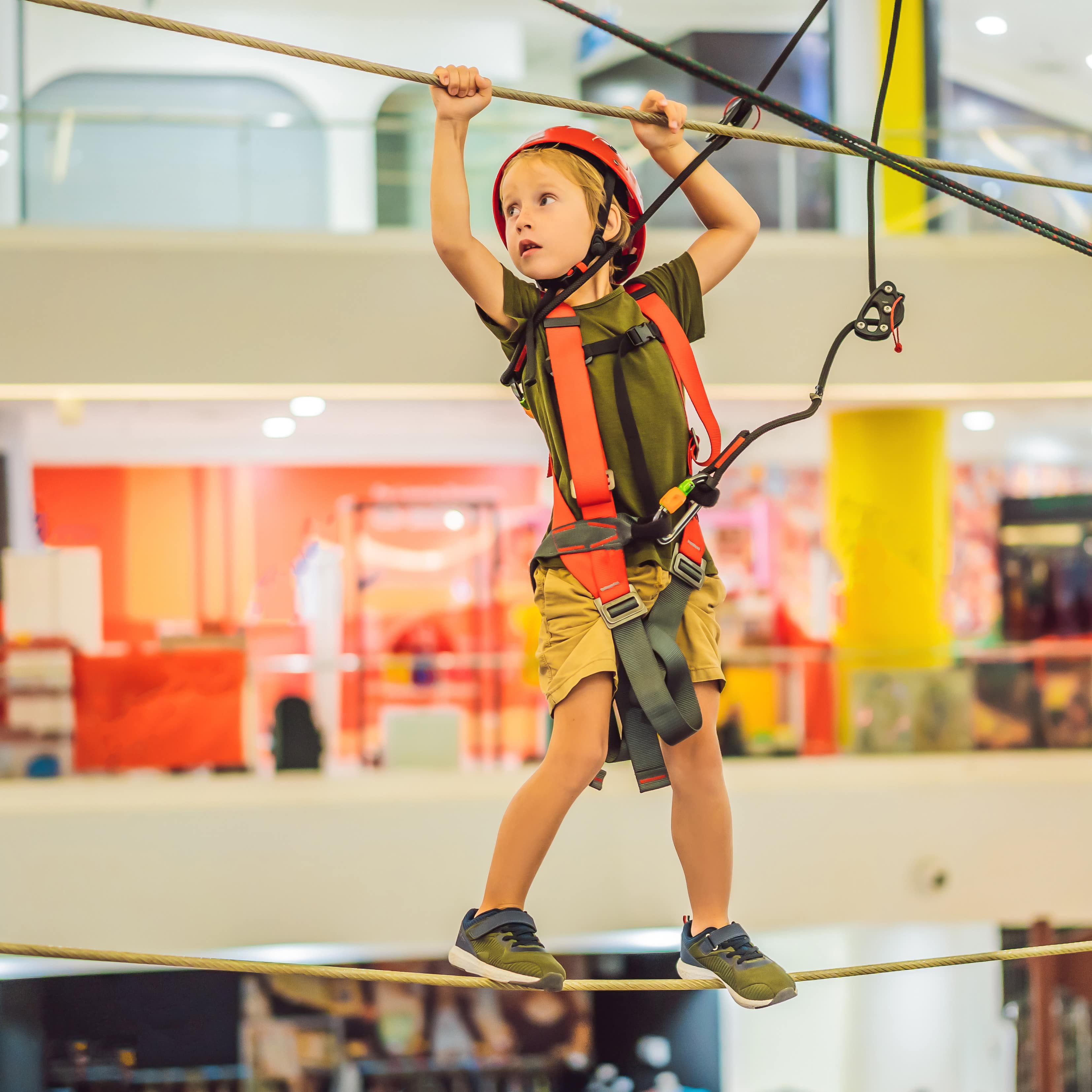 Ein Junge balanciert auf einer Kletter-Attraktion in einem Einkaufszentrum.