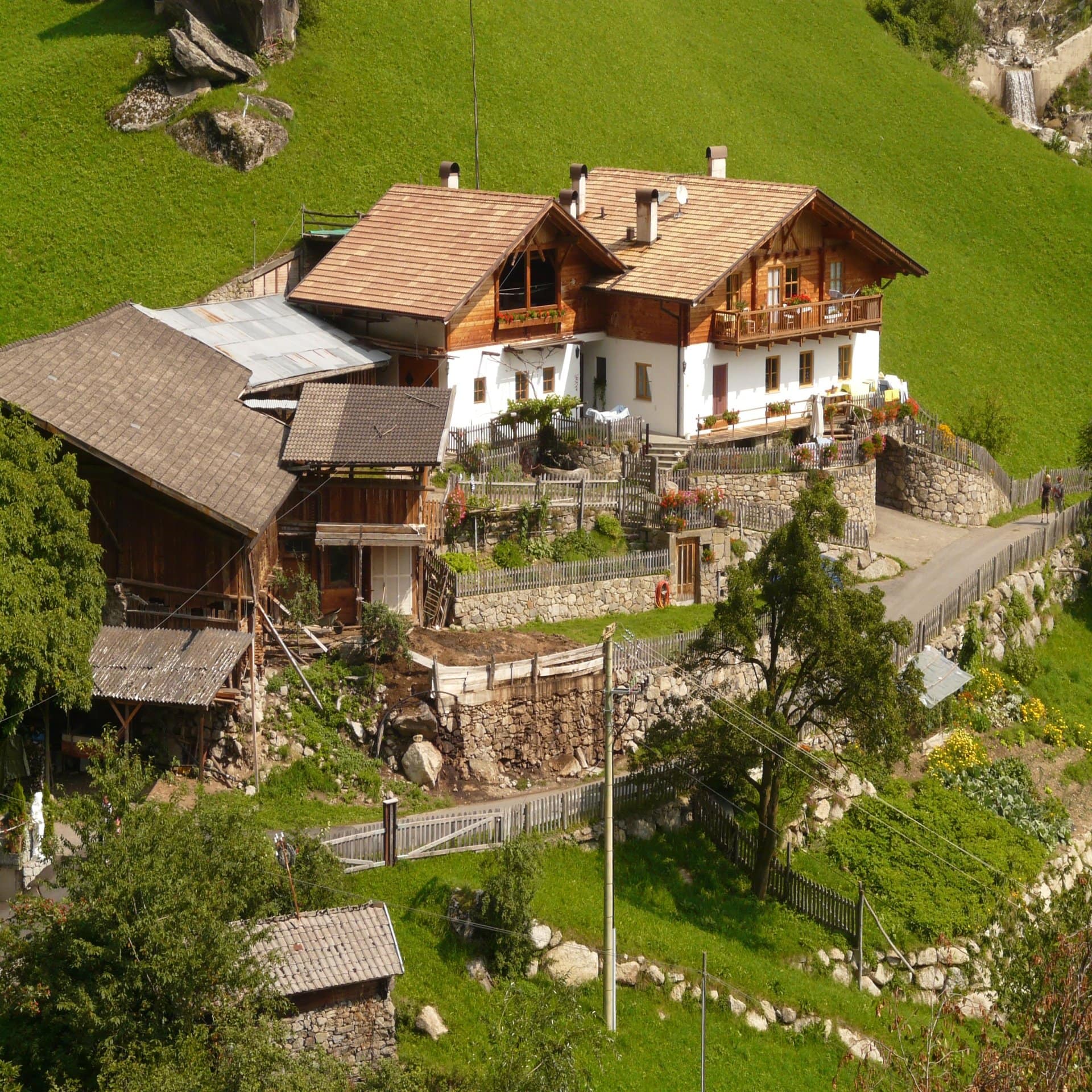 Bergbauernhof mit Stall und Scheune im Allgäu auf einer grünen Bergwiese. 