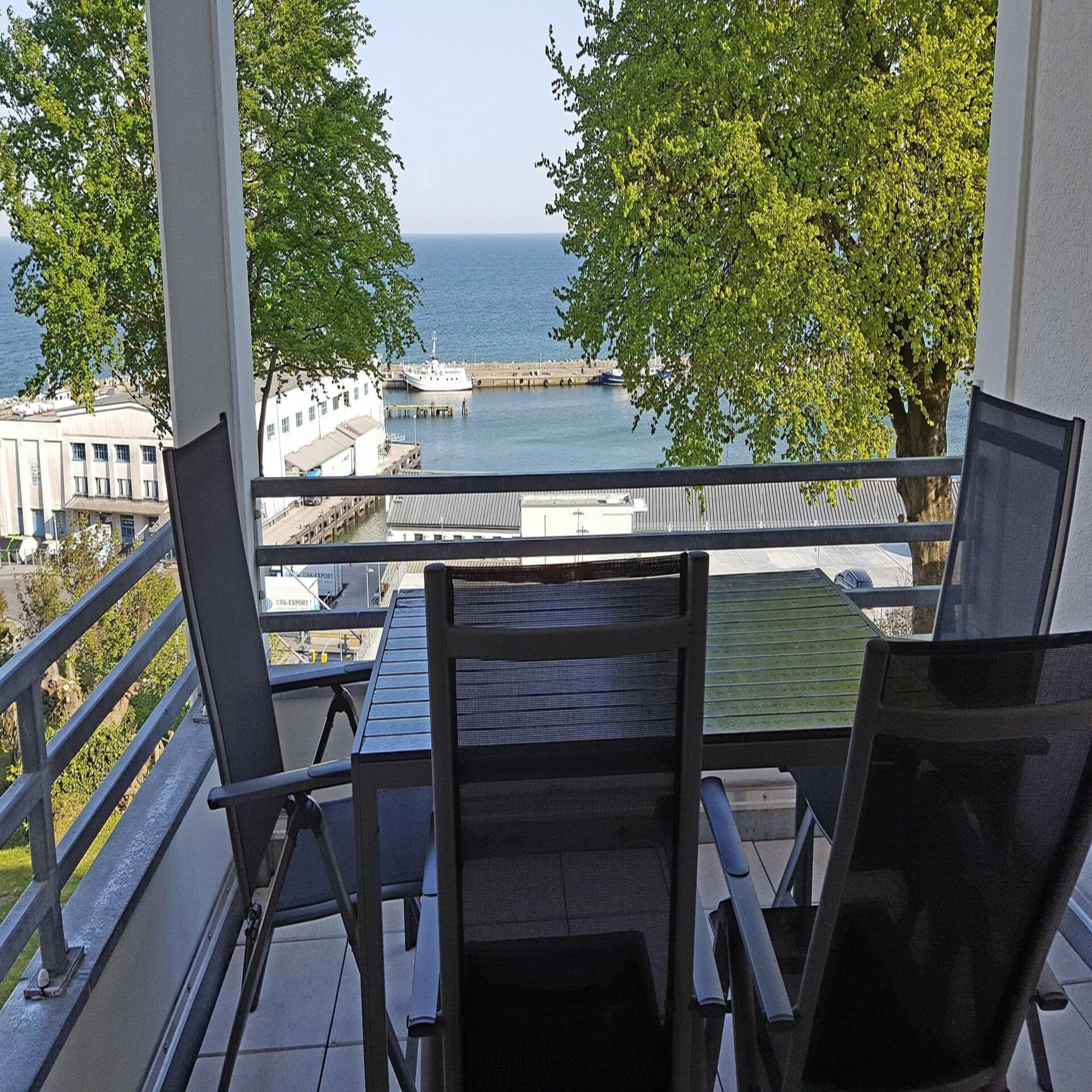 Balkon mit Tisch und Stühlen und Blick auf den Hafen von Sassnitz.