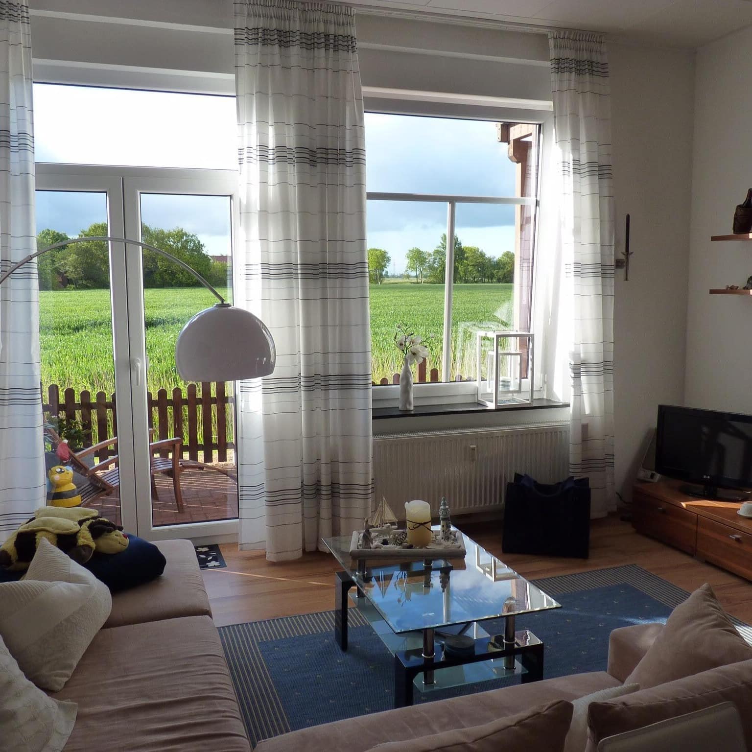 Wohnzimmer einer Ferienwohnung in Dornumersiel mit Blick auf die Terrasse und das Umland