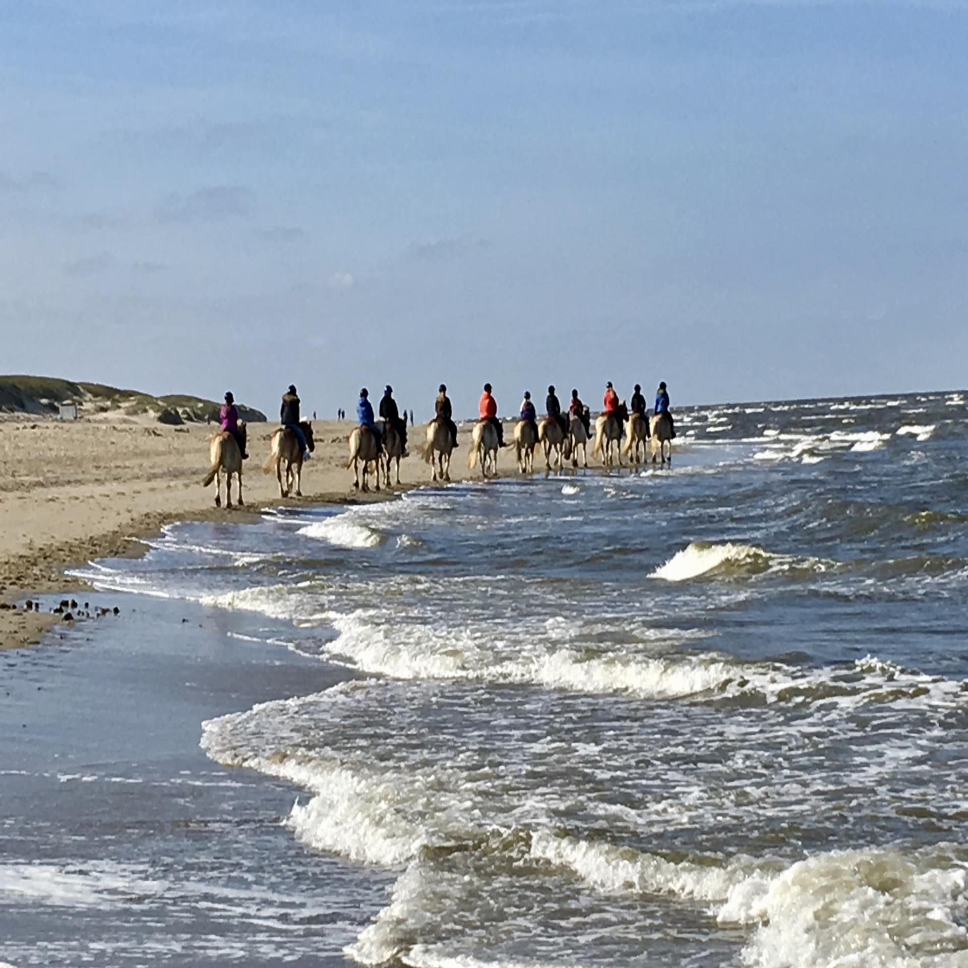 Eine Gruppe Reiter reitet am Strand entlang.