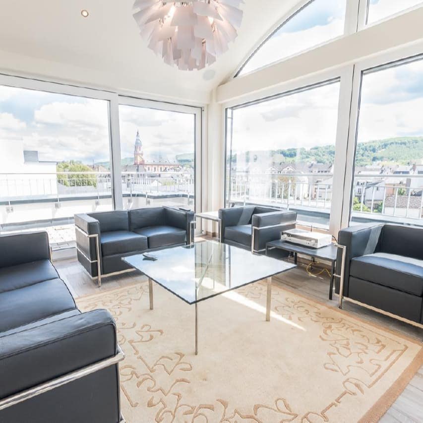 Wohnzimmer einer luxuriösen Ferienwohnung in Trier in der Altstadt, durch die großen Fenster ist die Altstadt zu sehen.
