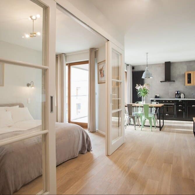 Bungalow in Swinemünde mit elegantem Interior – großer Wohn- und Schlafbereich mit Bett und offener moderner Küche