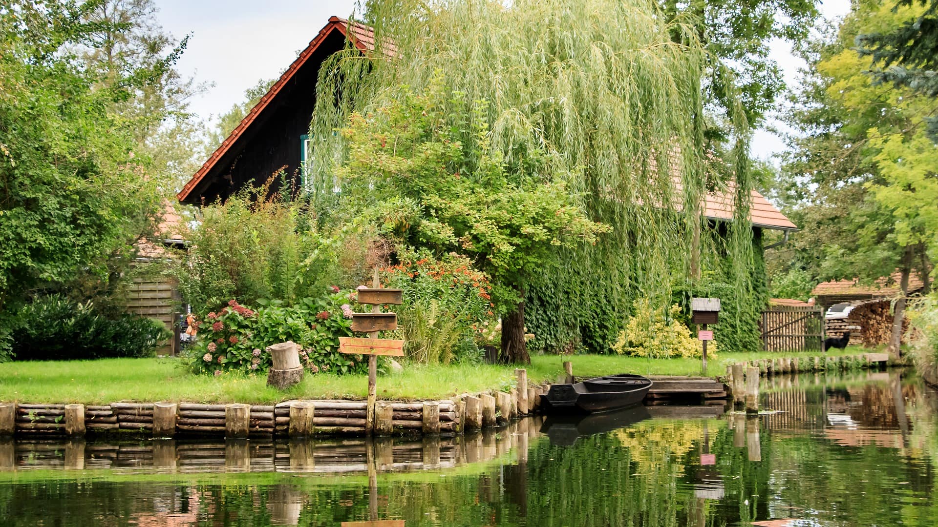 Haus von einem Baum verdeckt direkt am Wasser mit einem Boot