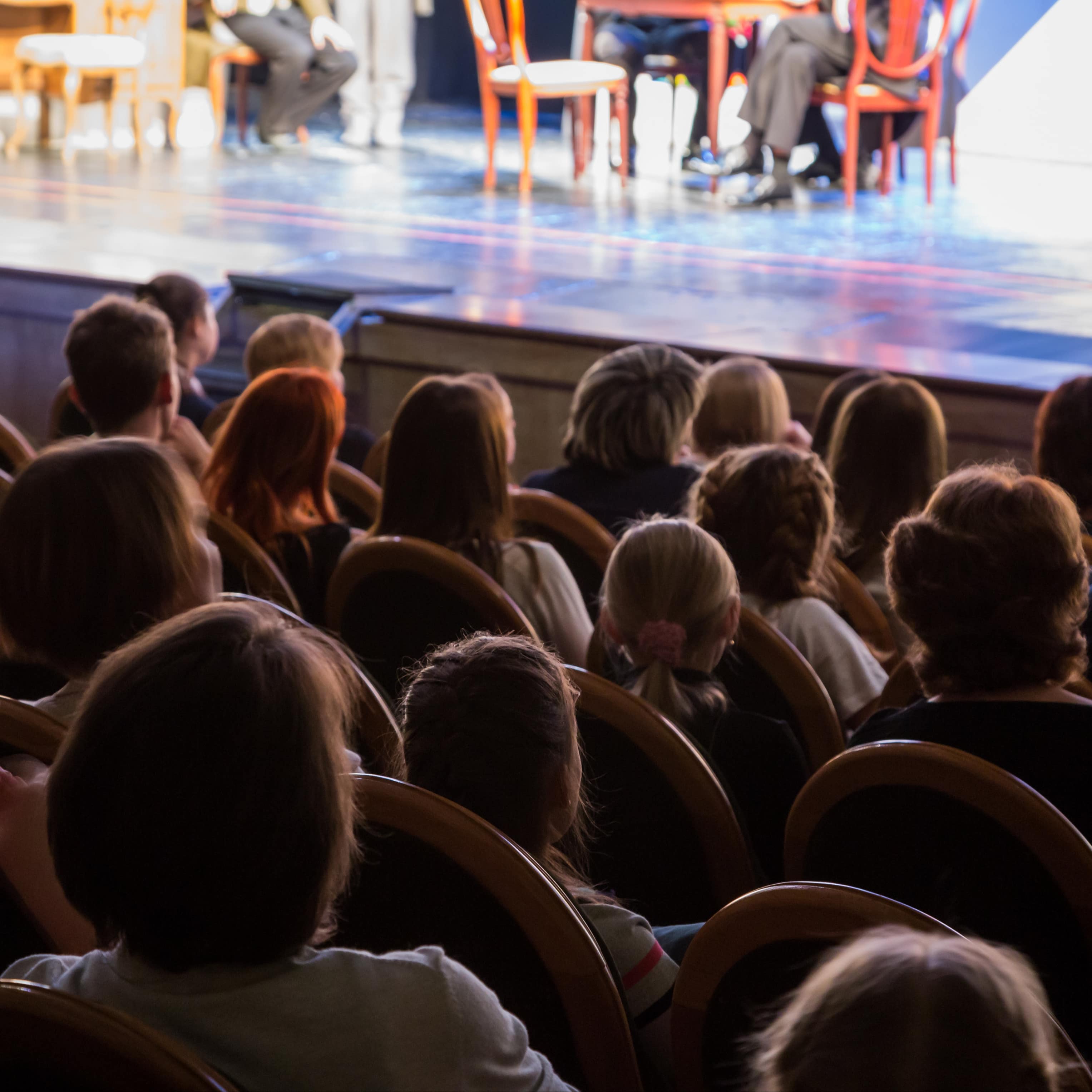 Blick von hinten auf Erwachsene und Kinder im Theater während einer Vorstellung.