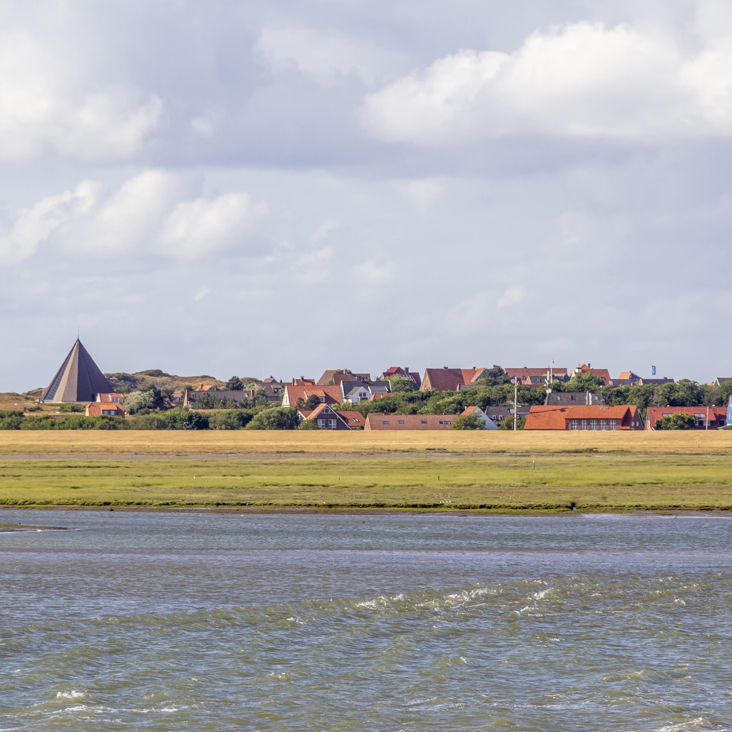 Blick von einem Boot aus über das Wasser auf Land und die Häuser von Spiekeroog.