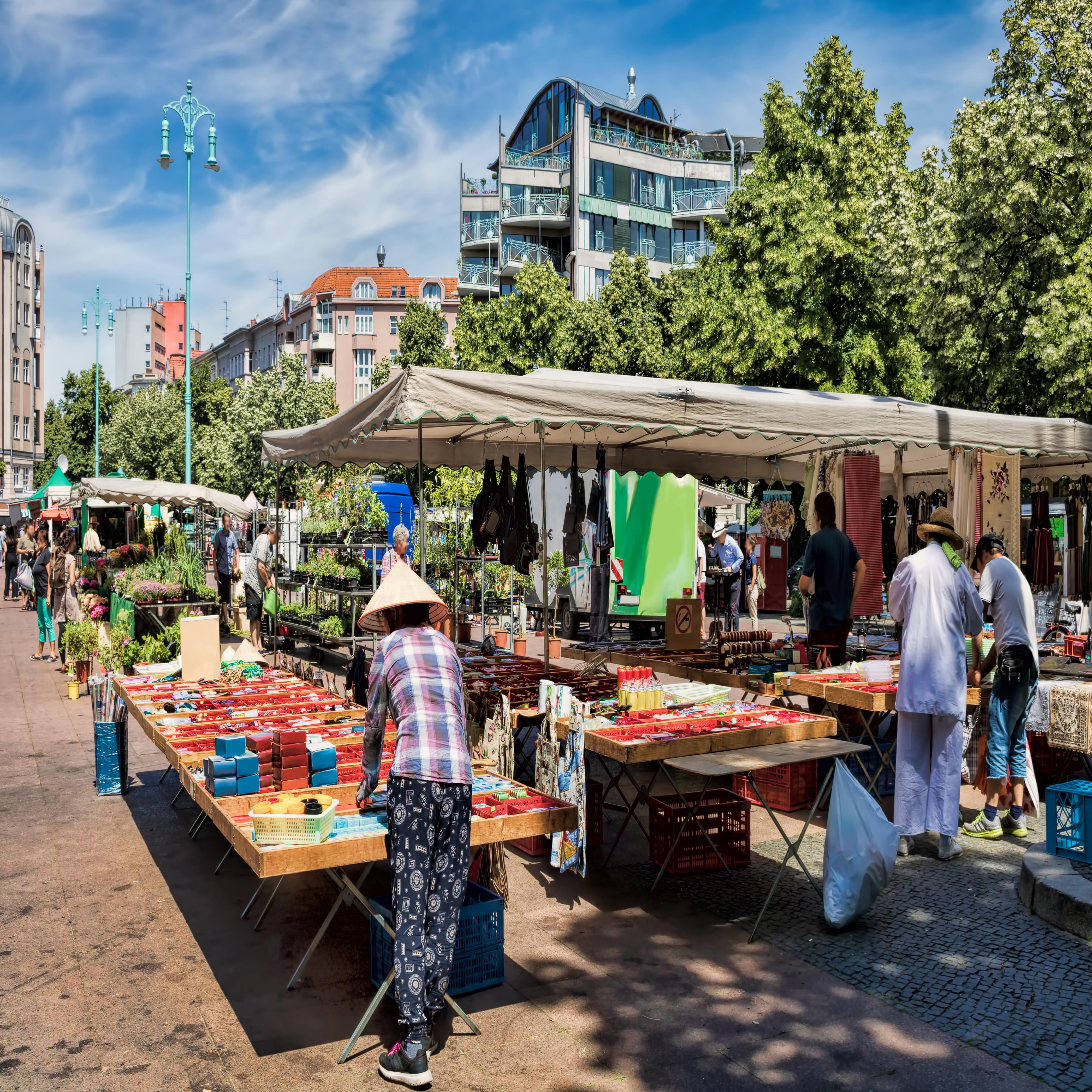 Blick über einige Stände eines Wochenmarkts in Berlin. Im Hintergrund Wohnhäuser.