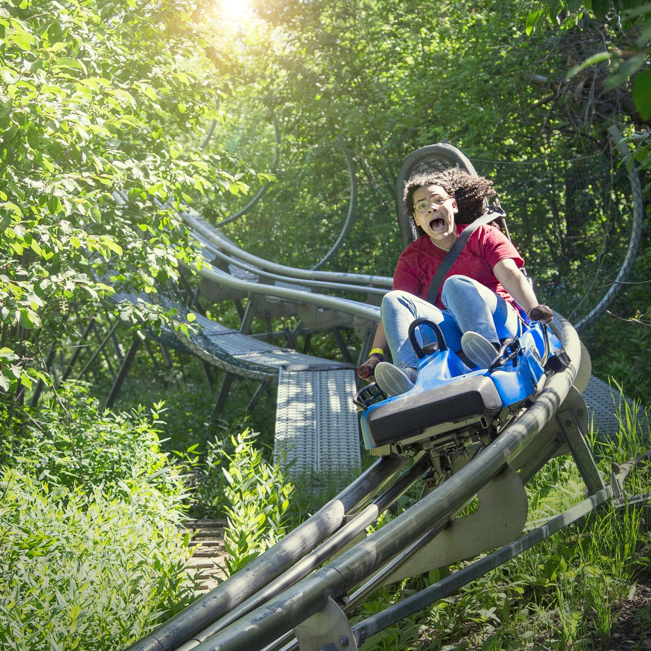 Ein Mädchen hat Spaß auf der Sommerrodelbahn.