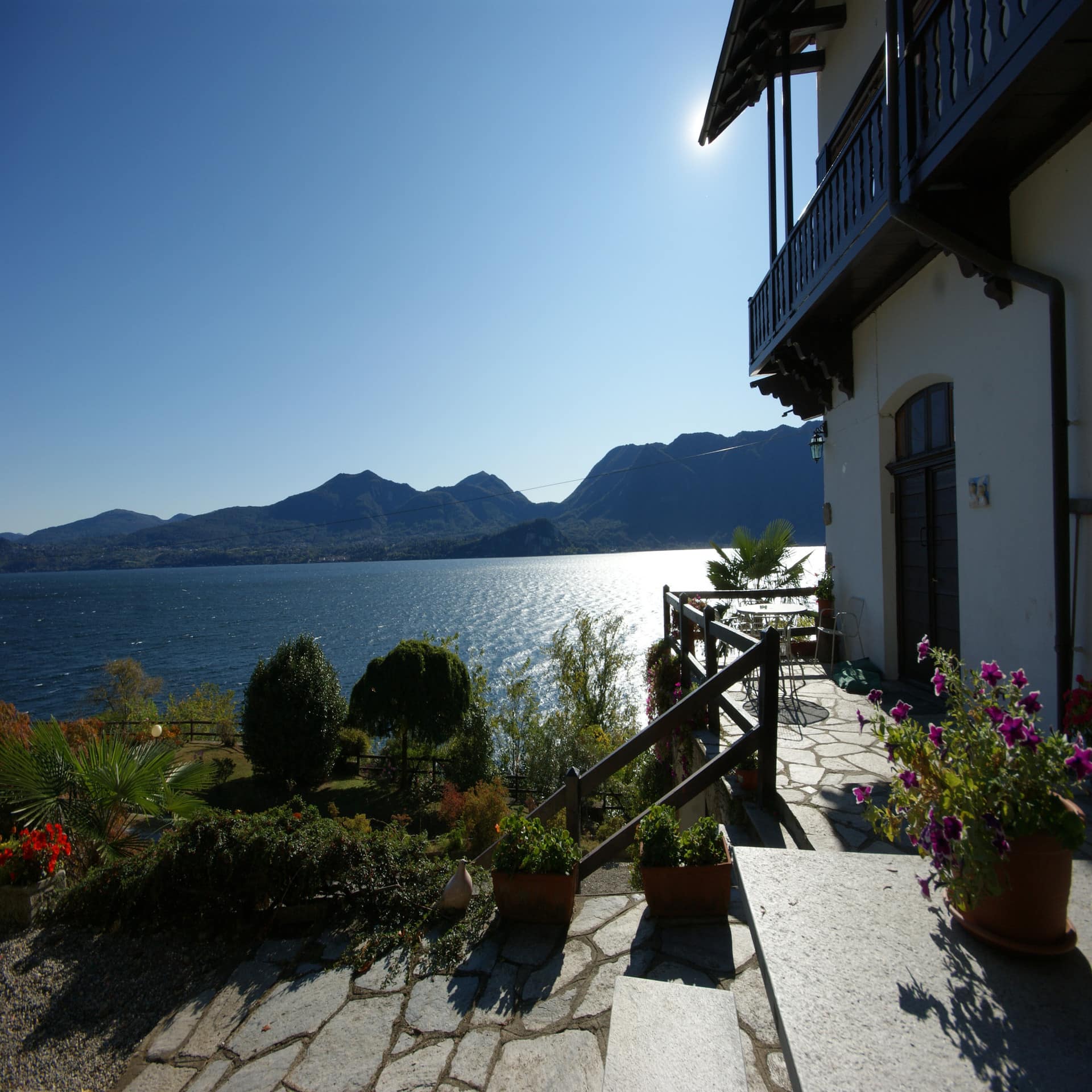 Garten eines Hauses direkt am See mit Blick auf den See. Blauer Himmel und Sonnenschein. 