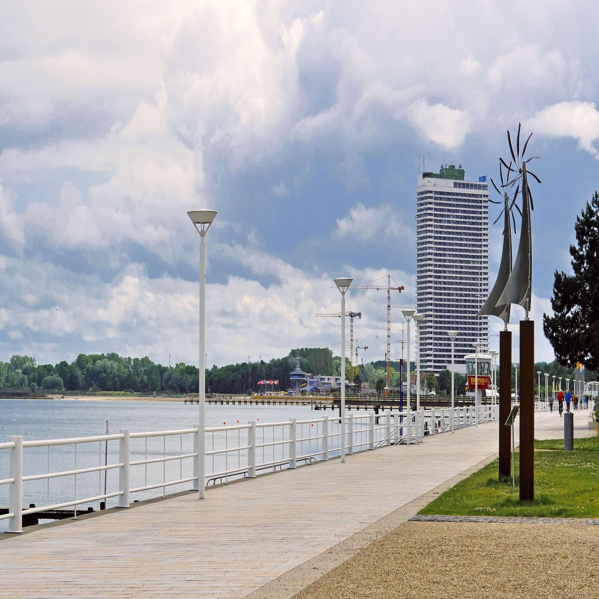 Blick entlang der Promenade von Travemünde, ein Hochhaus im Hintergrund.