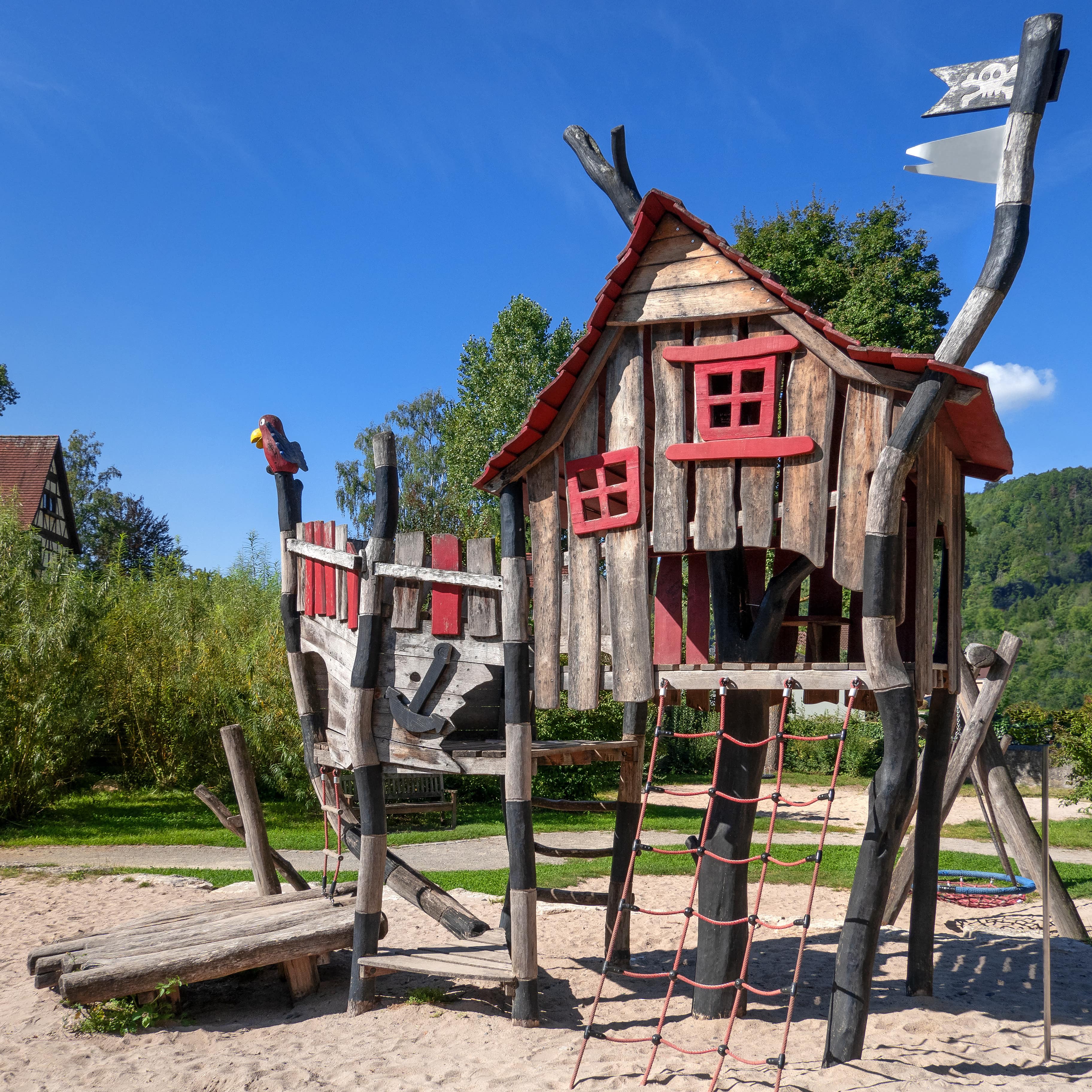 Ein Abenteuerspielplatz: Klettergerüst mit Haus, drumherum Sand.
