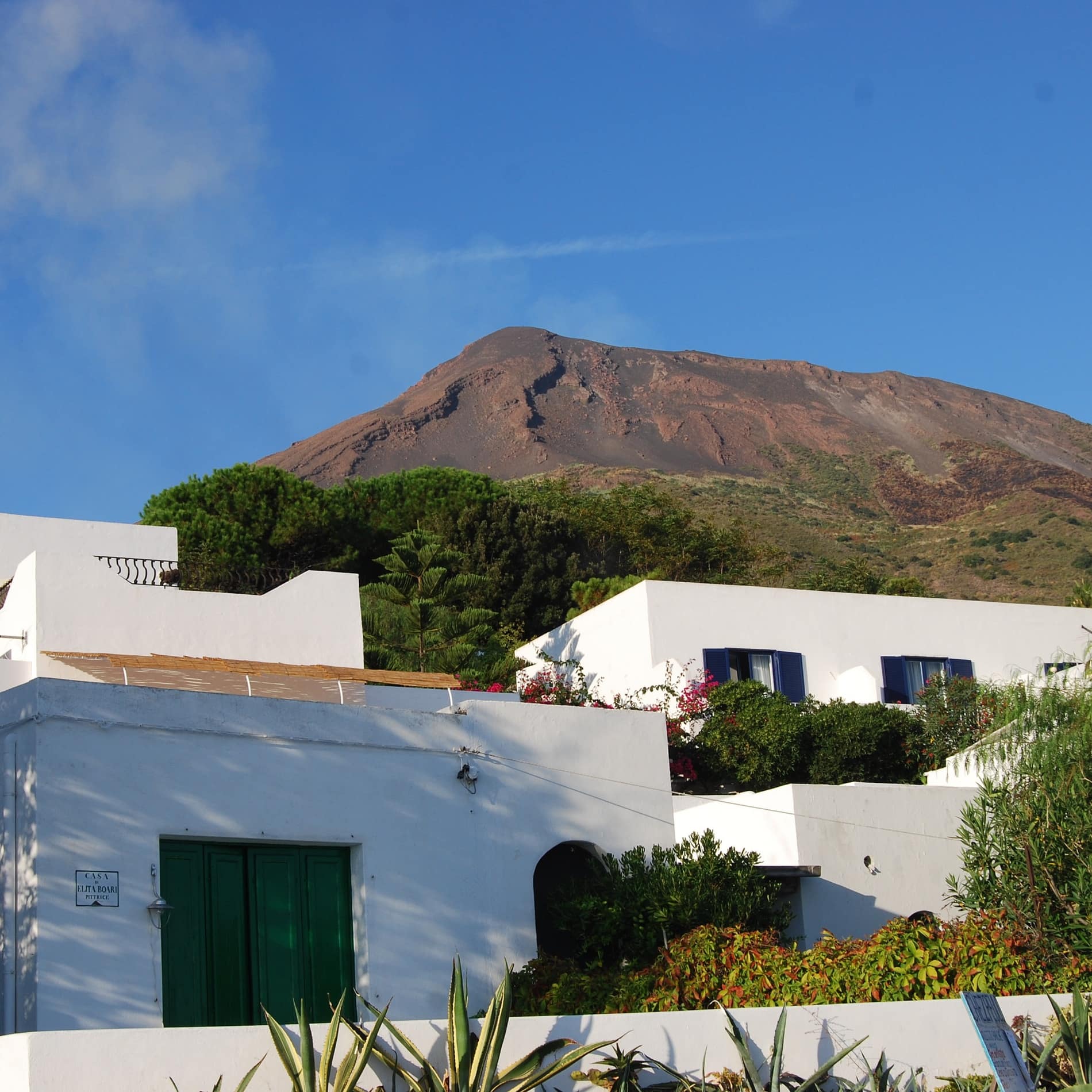 Hinter der Ferienwohnung in Sizilien ist gegen das Blau des Himmels der aufsteigende Rauch des Vulkans Stromboli zu erkennen