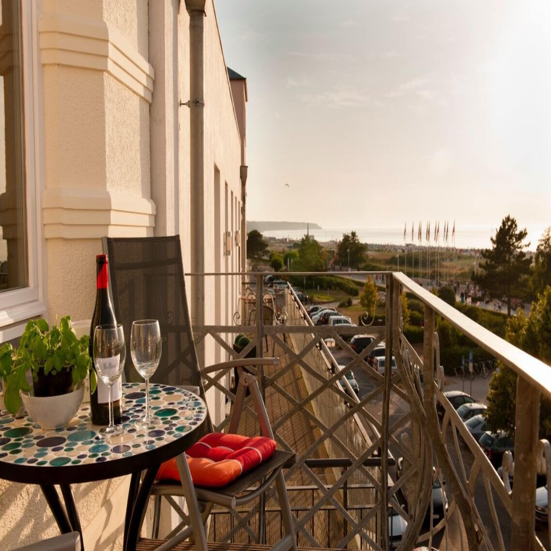 Balkon mit Tisch, Stuhl und Wein sowie Blick auf die Ostsee bei Sonnenuntergang.