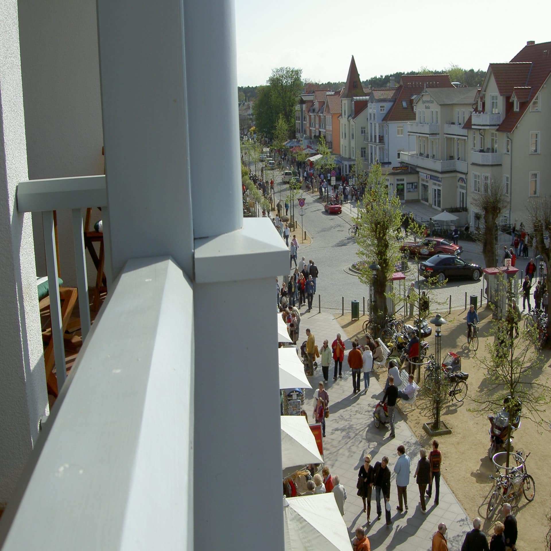 Blick vom Balkon auf das bunte Treiben in der Sandtraße in Kühlungsborn Ost. Es ist Frühling.