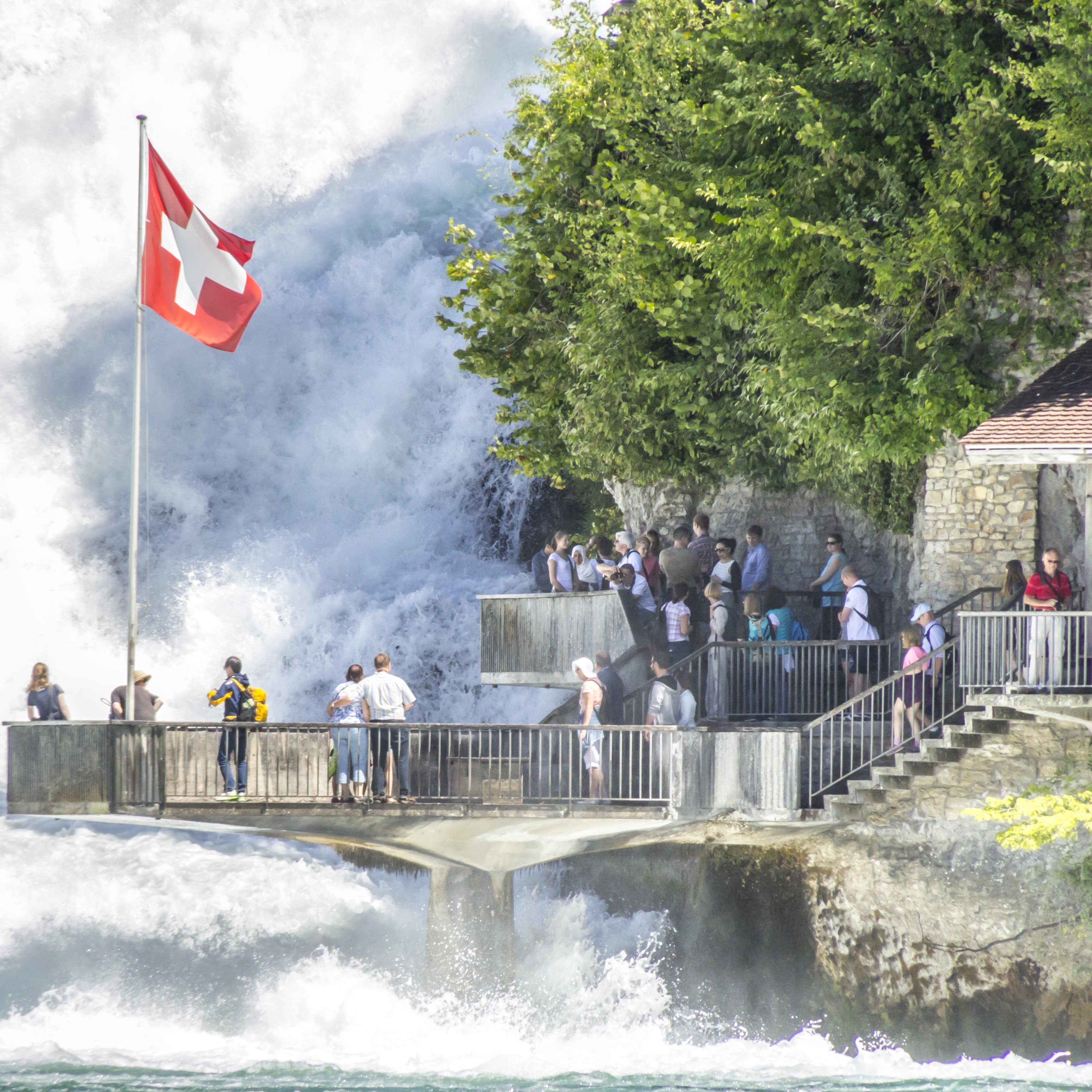 Leute auf der Besucherplattform am Rheinfall. Die Schweizer Flagge weht.