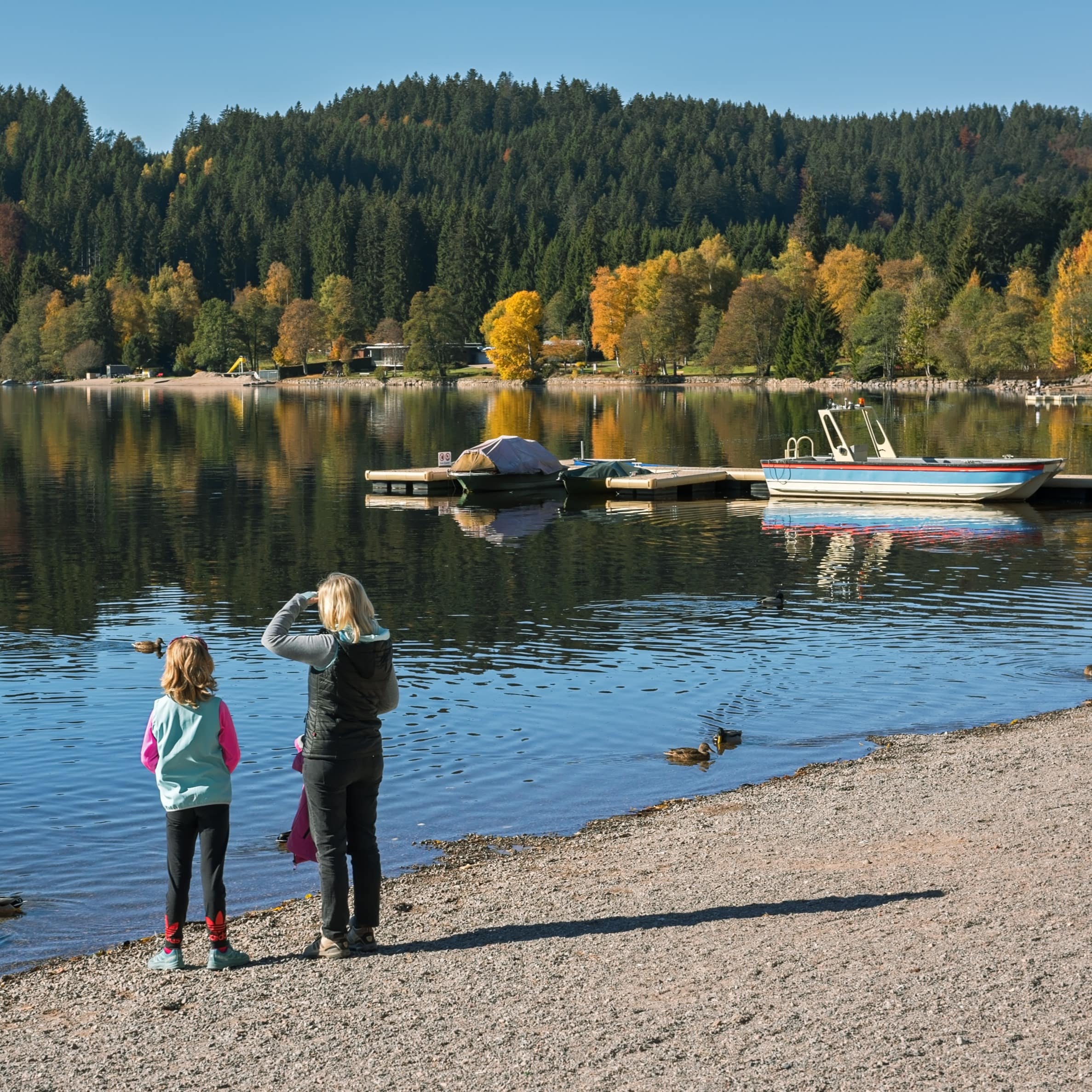 Eine Frau und ein Kind am Ufer des Titisee.