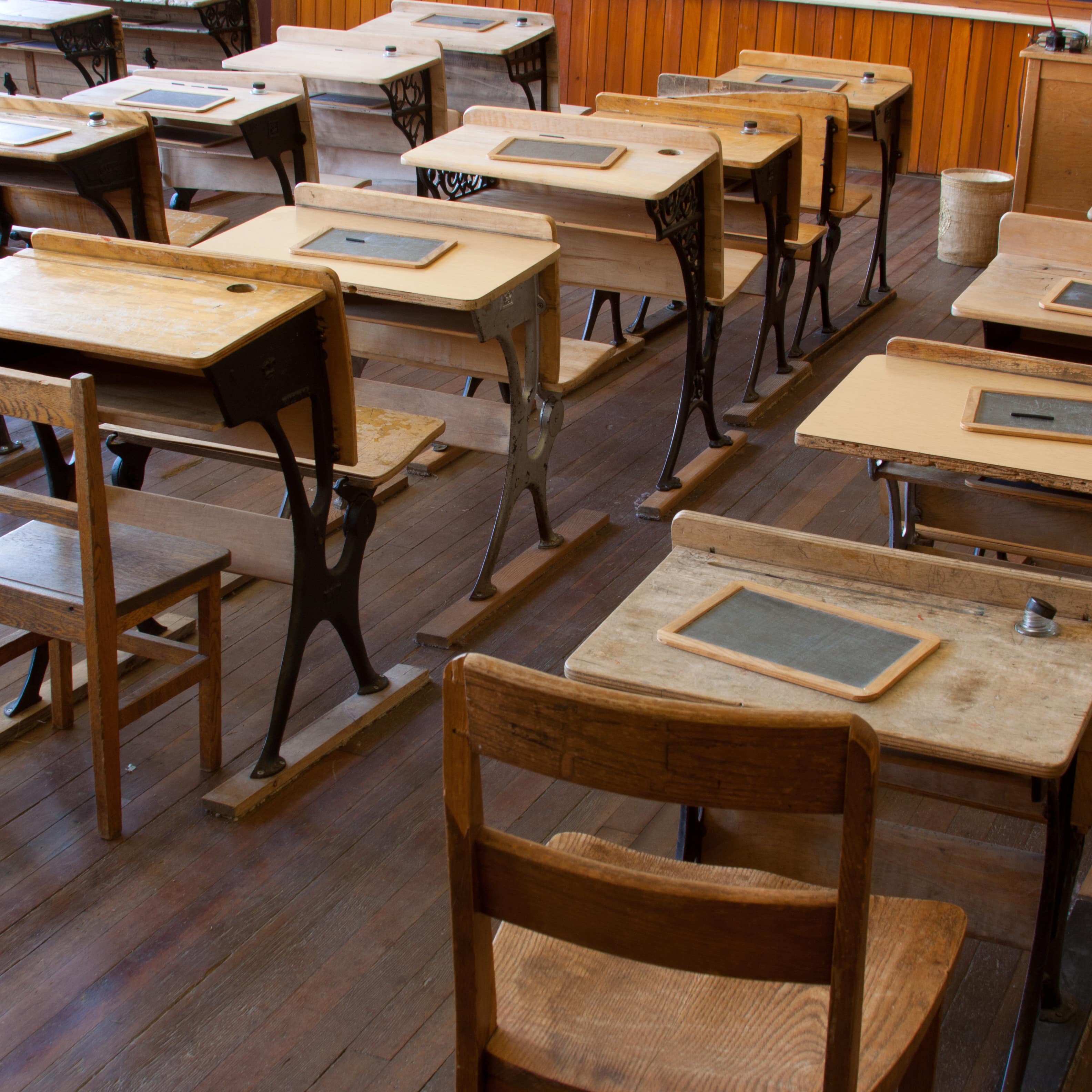 Historisches Klassenzimmer mit Holzmobiliar, auf jedem Schreibtisch eine Schiefertafel.