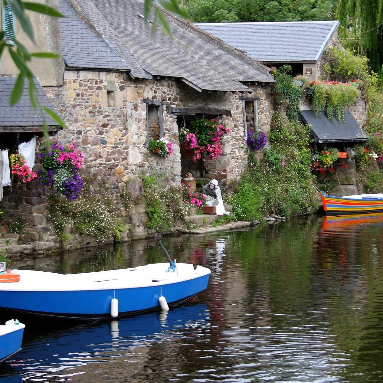 Kleine Steinhäuser direkt am Wasser in der Bretagne, Ruderboote schwimmen im Wasser