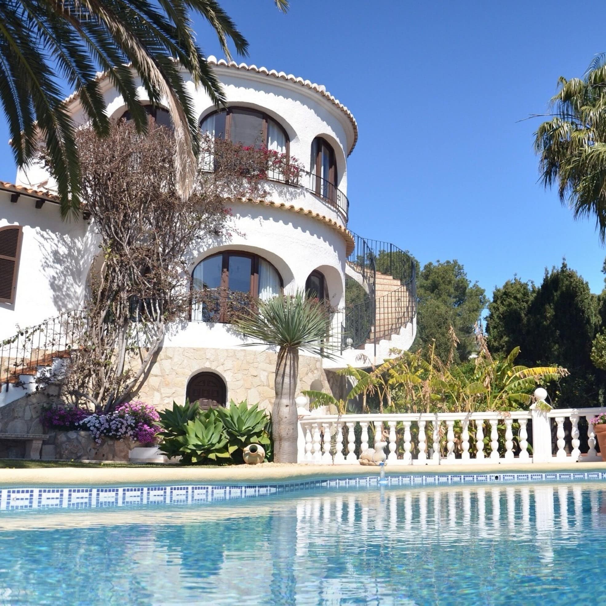 Villa mit Treppe zum Pool und Bäumen im Hintergrund