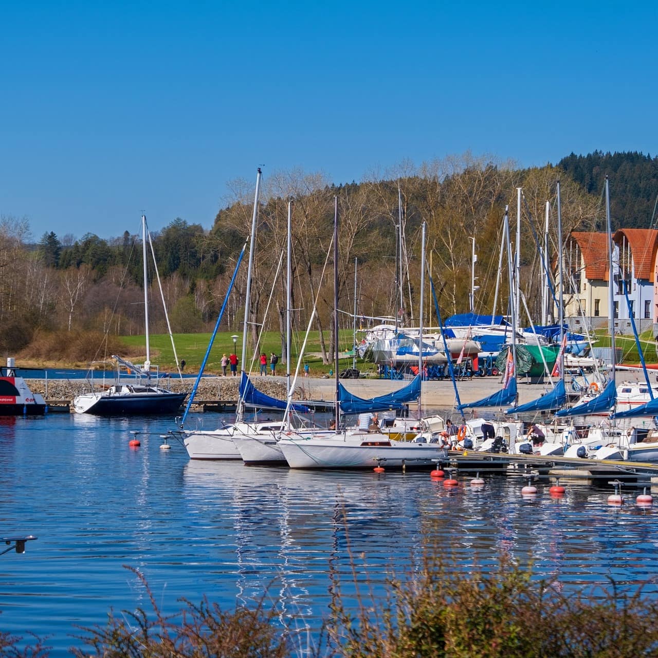 Blick auf den Hafen des Moldaustausees in dem kleine Boote ankern, seitlich sind Häuser zu sehen