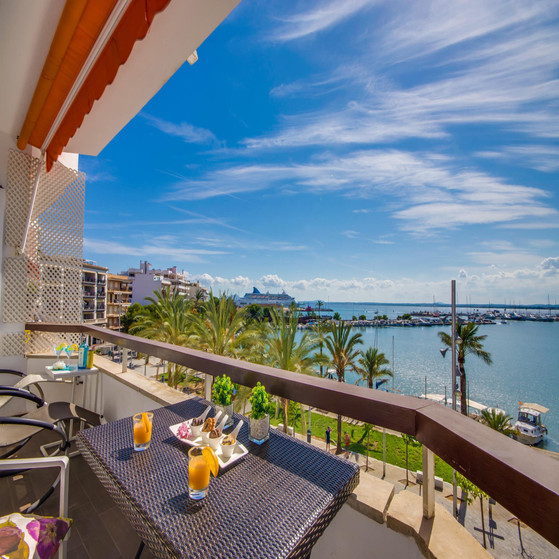 Balkon mit Tisch und Stühlen und Blick auf Palmen und das Meer.