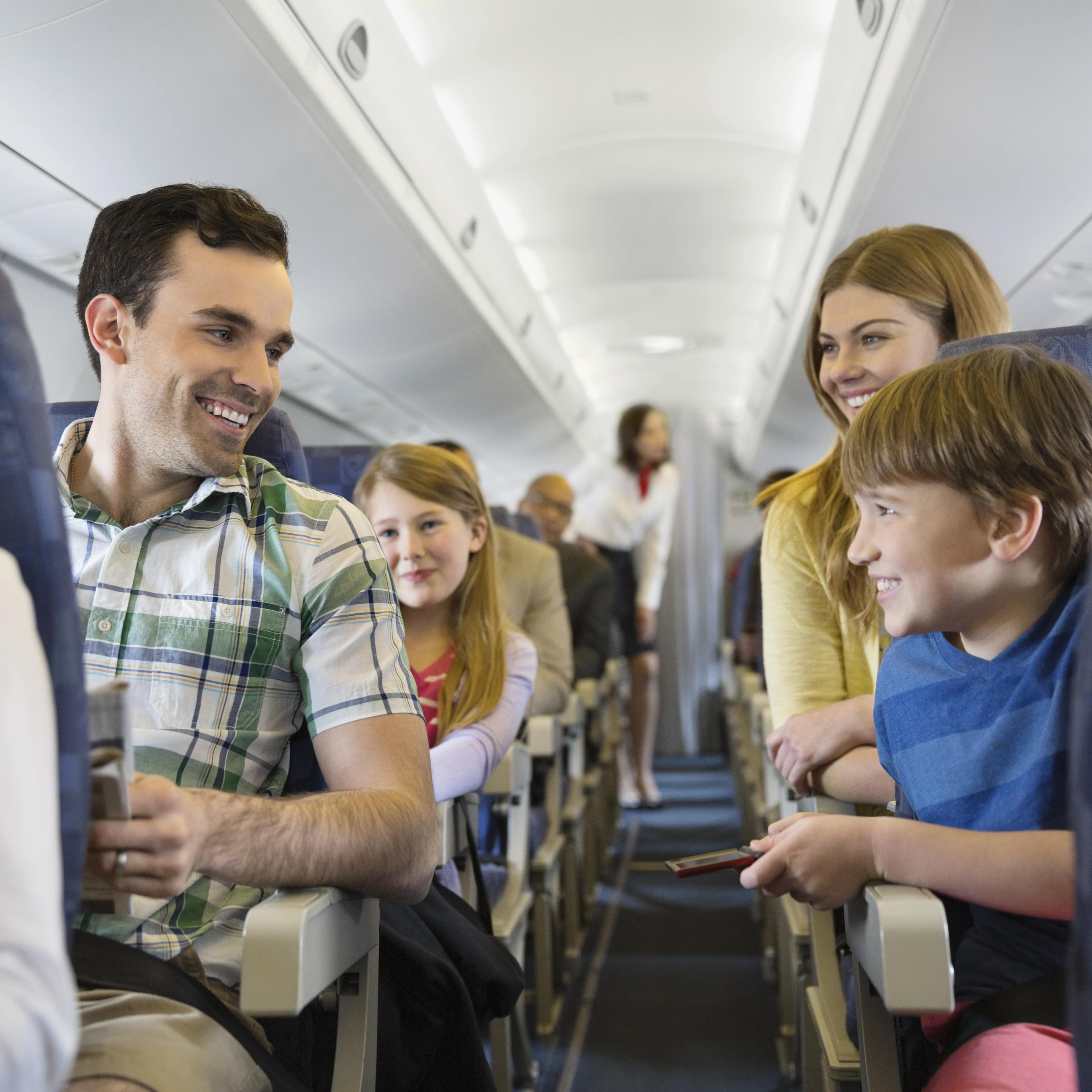 Lächelnde Familie mit 2 Kindern im Flugzeug.