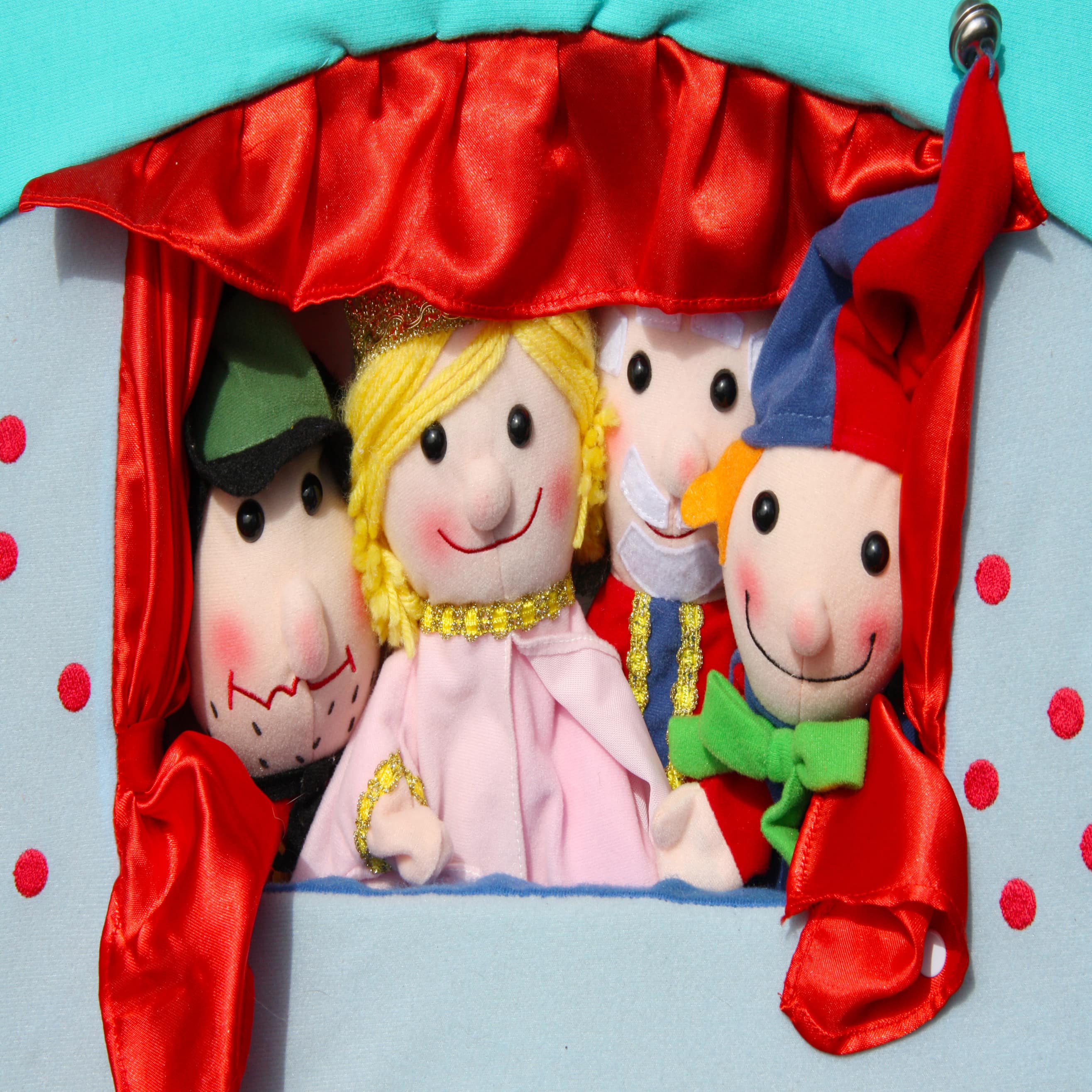 4 lächelnde Figuren in einem Kasperle Theater mit rotem Vorhang.