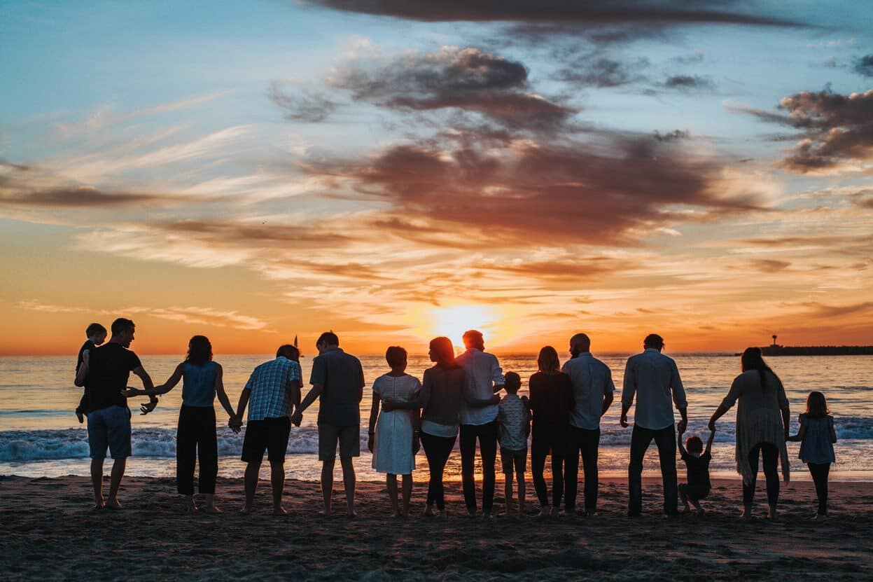 Familie an einem Strand mit Blick auf den Sonnenuntergang