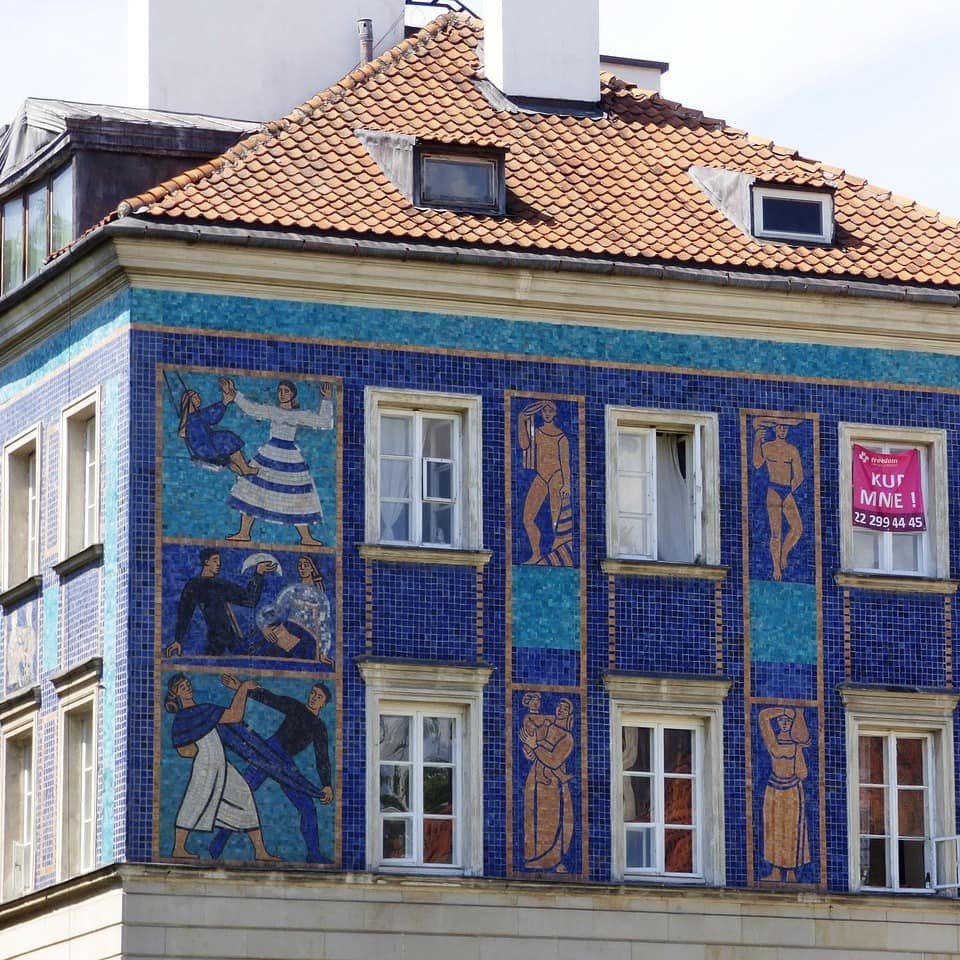 Ein Altbau in Polen mit blauen Mosaik-Verzierungen und weißen Sprossenfenstern