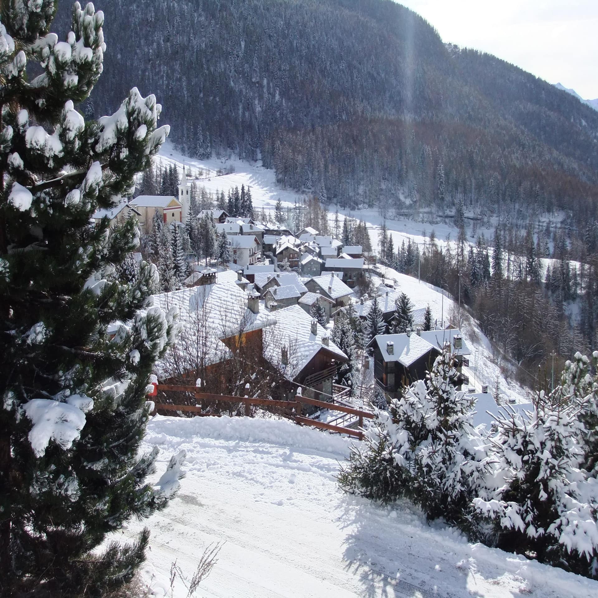 Blick über das verschneite Bergdorf La Magdeleine auf 1.700 Metern unweit des Matterhorns im Aostatal. Die Sonne scheint. 