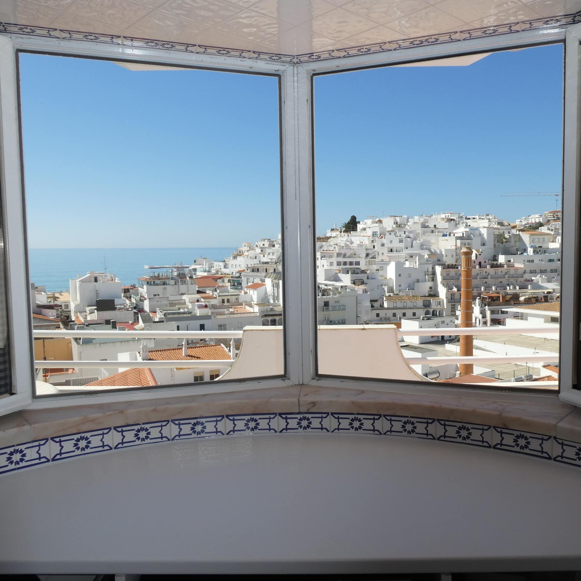 Blick aus dem Küchenfenster einer Ferienwohnung in Albufeira auf die weißen Häuser und das Meer