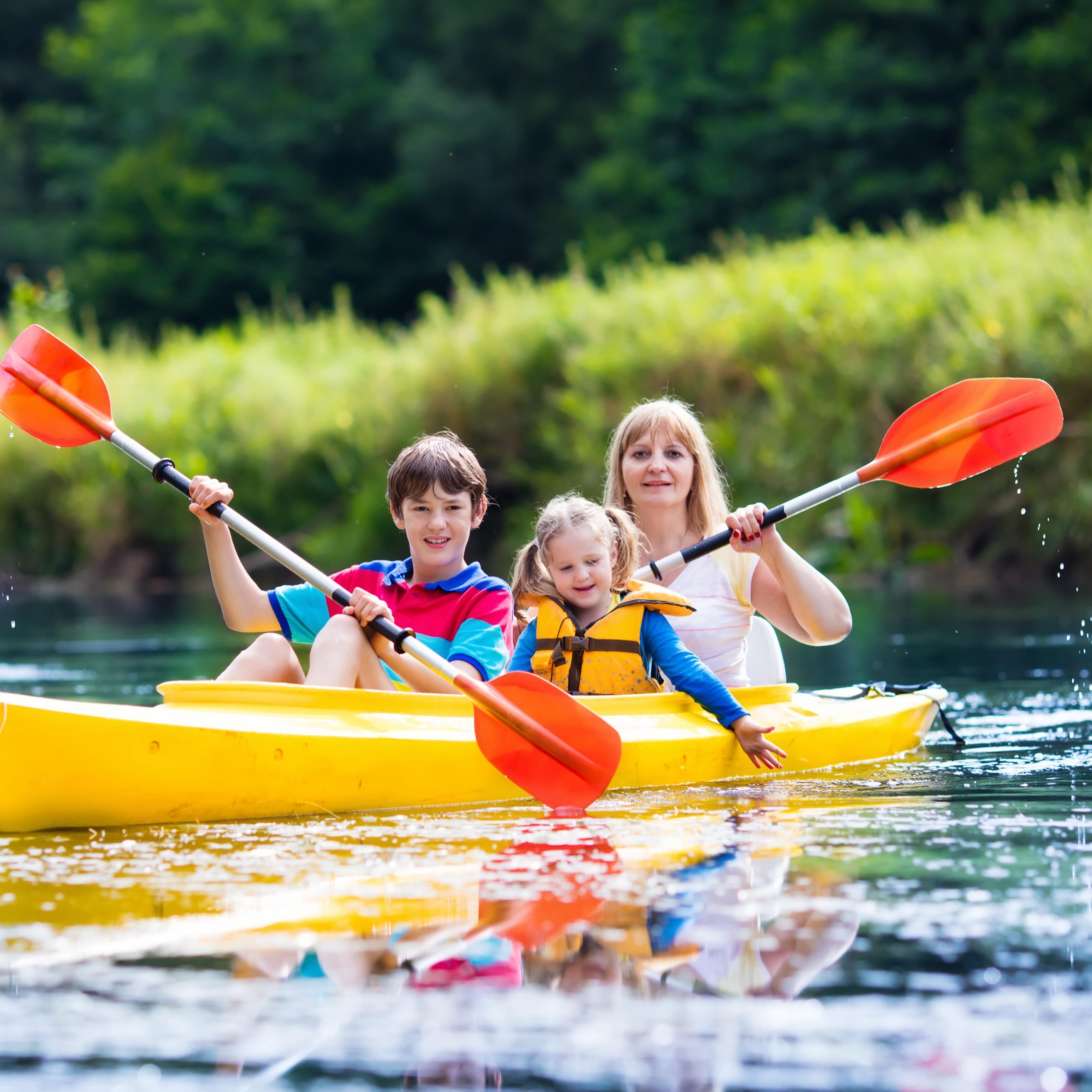 Mutter und 2 Kinder ein einem gelben Kanu auf dem Fluss.