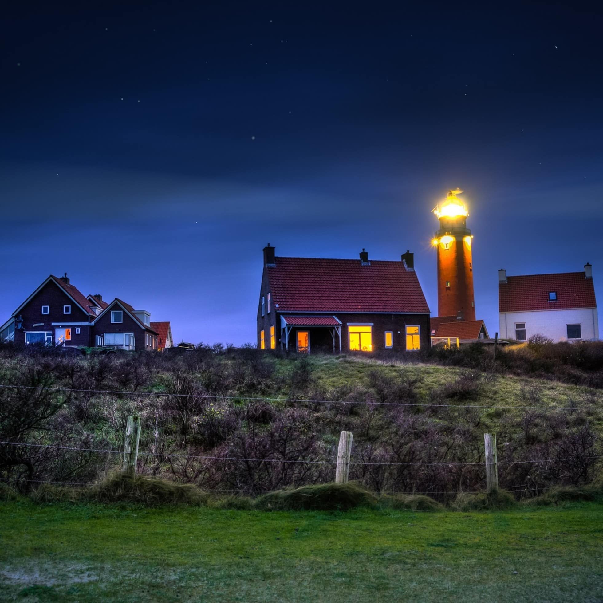 Bungalows auf Texel im Abendlicht und Schein des Leuchtturms