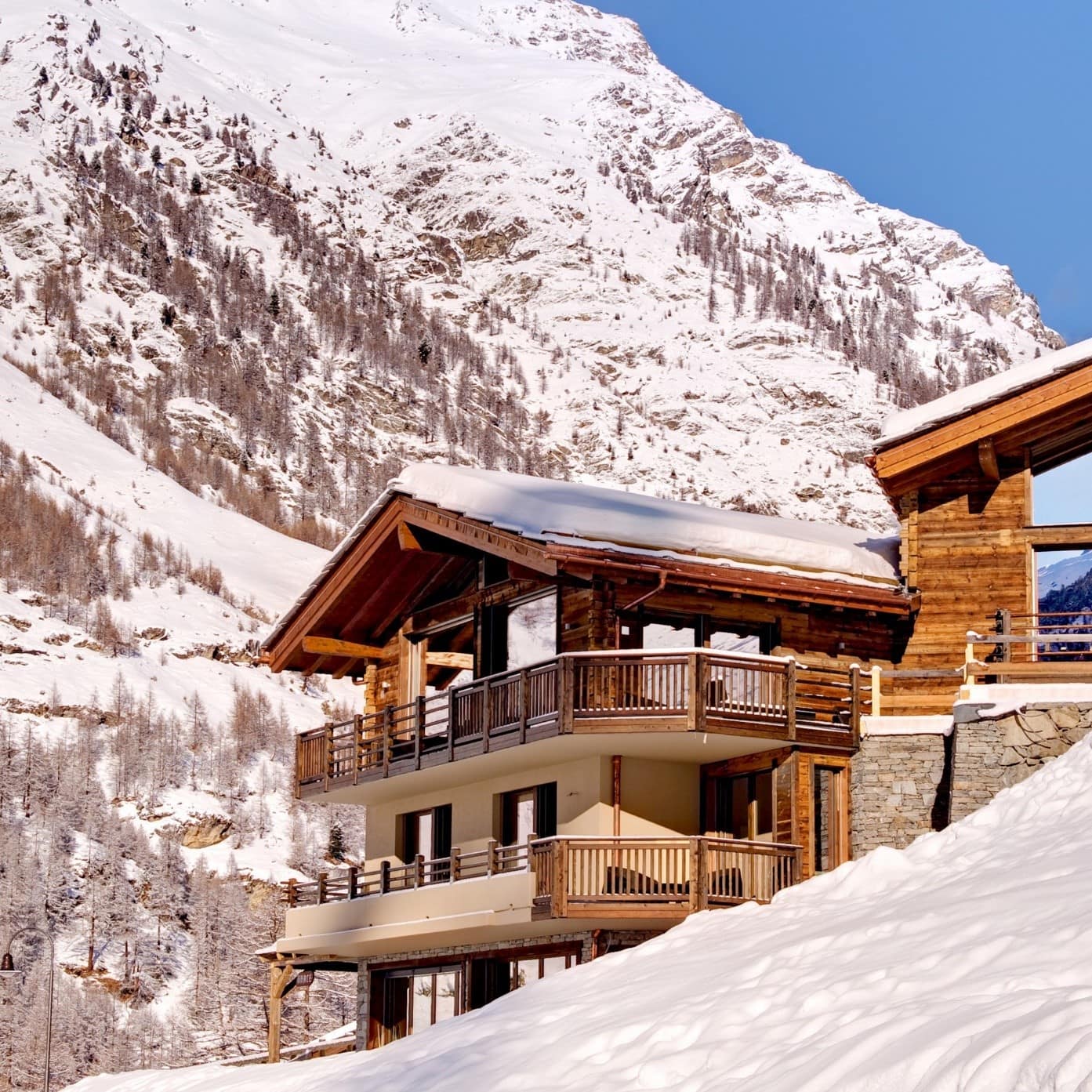 Alpenchalet mit schneebedecktem Dach in direkter Hanglage im Winter