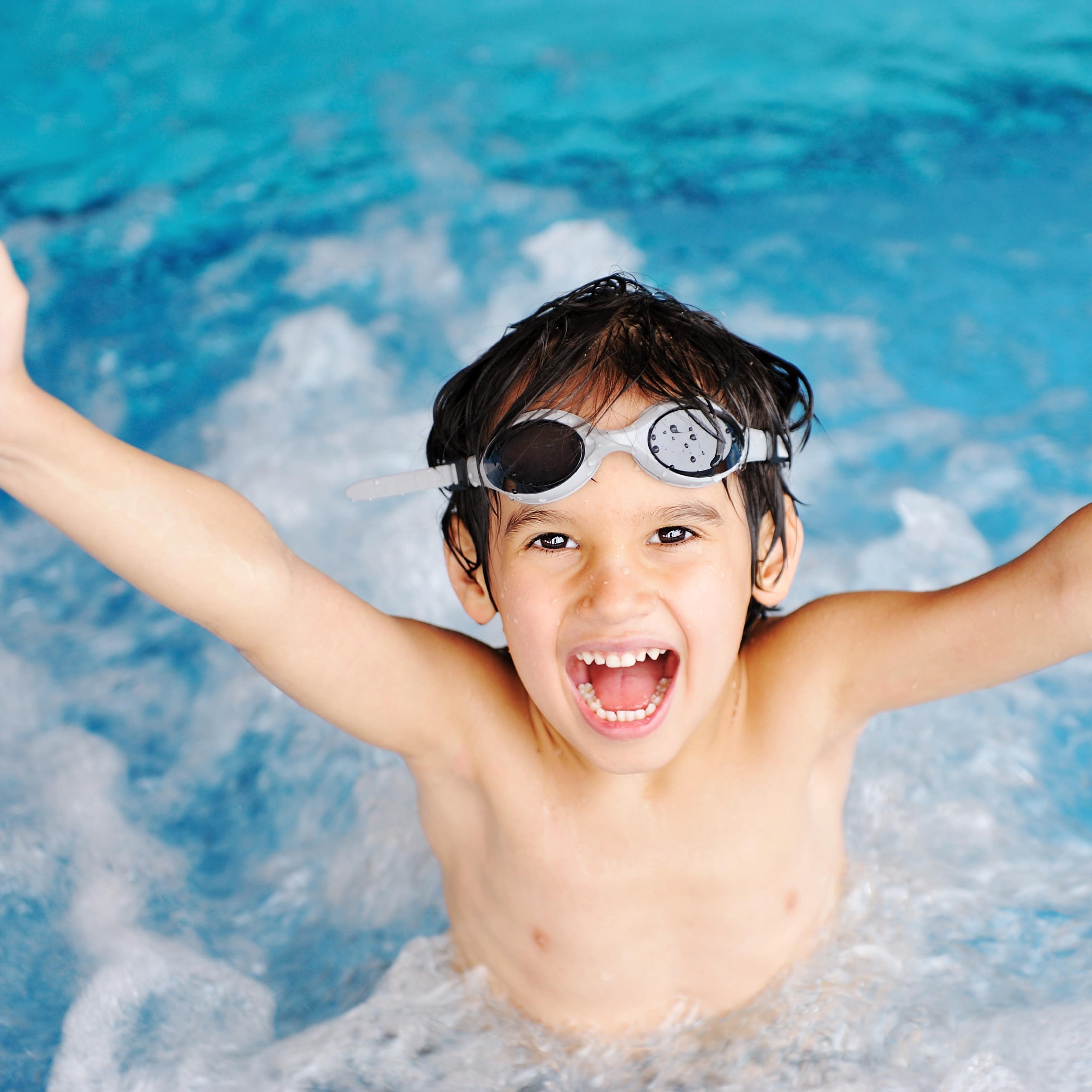 Ein jubelnder Junge in einem Schwimmbad