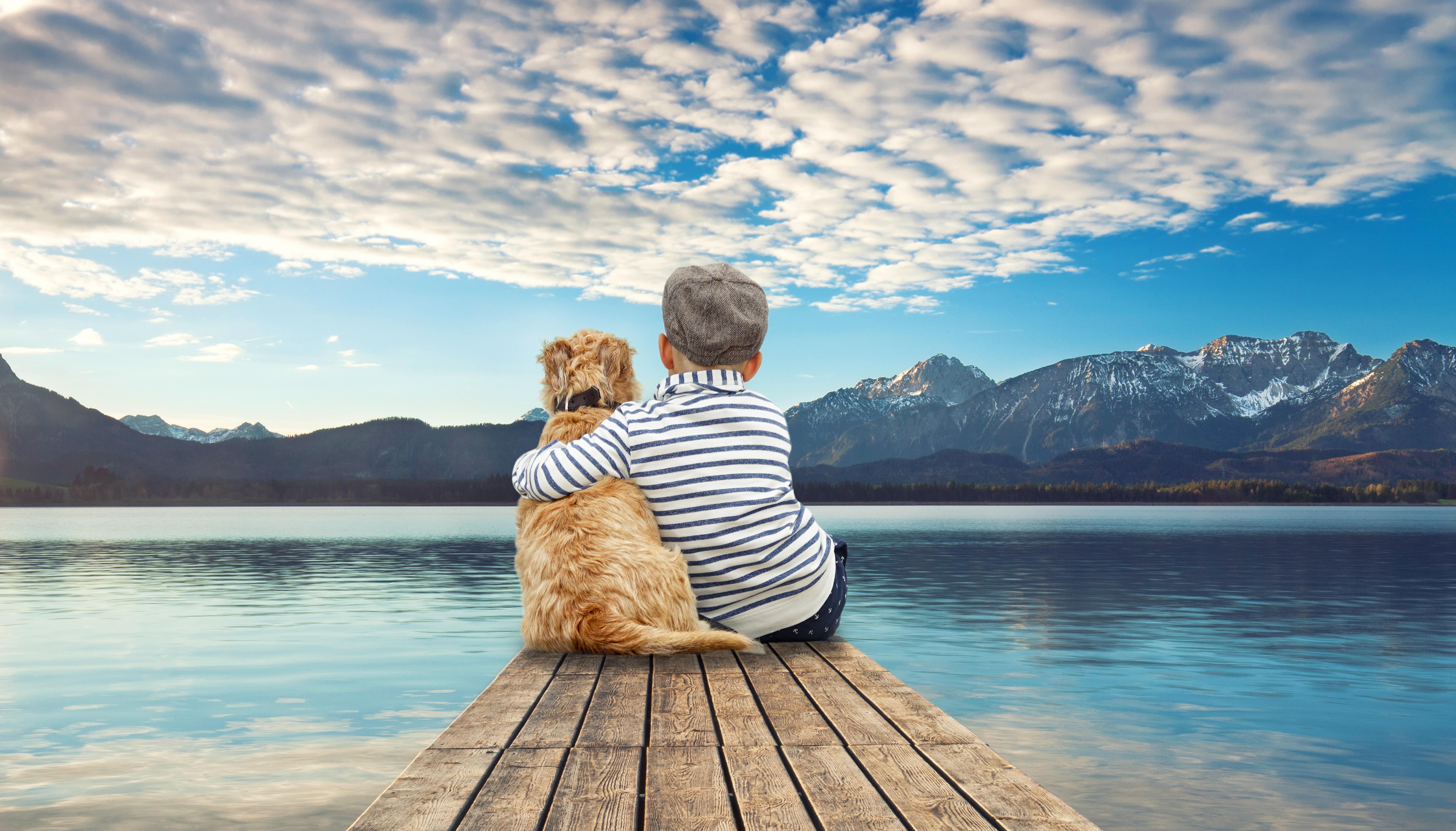 kleiner Junge mit Hund vor einem See