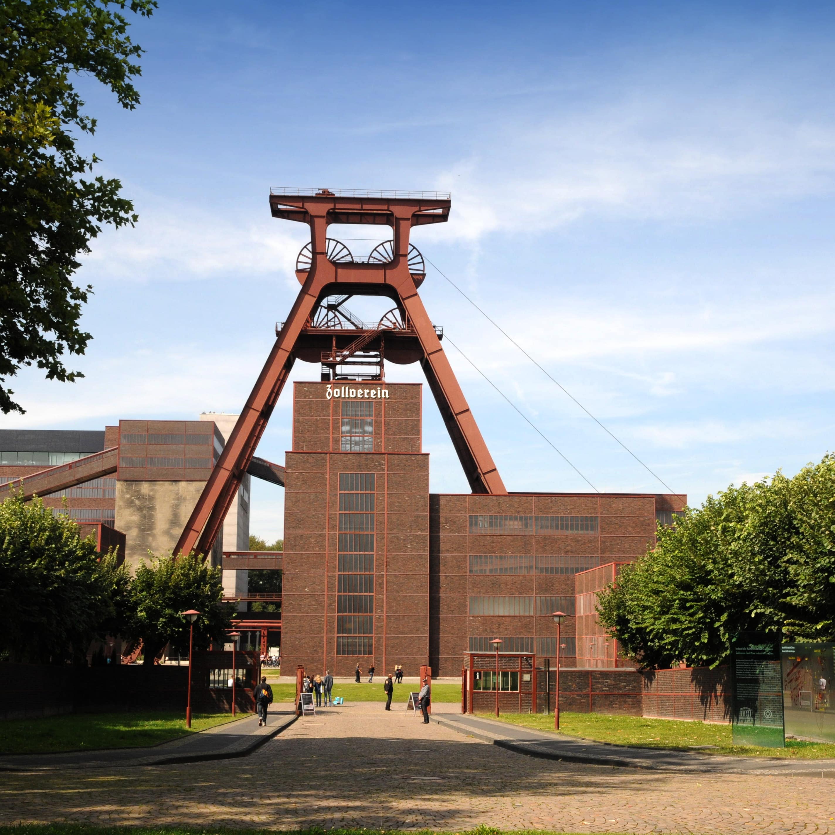 Blick auf die Zeche Zollverein, vor der Personen stehen.