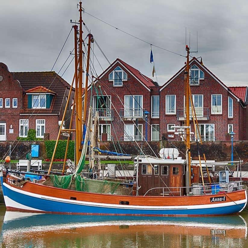 Typisch rote Backsteinfassaden der Häuser, die direkt am Wasser liegen. Im Wasser ankert ein Boot.