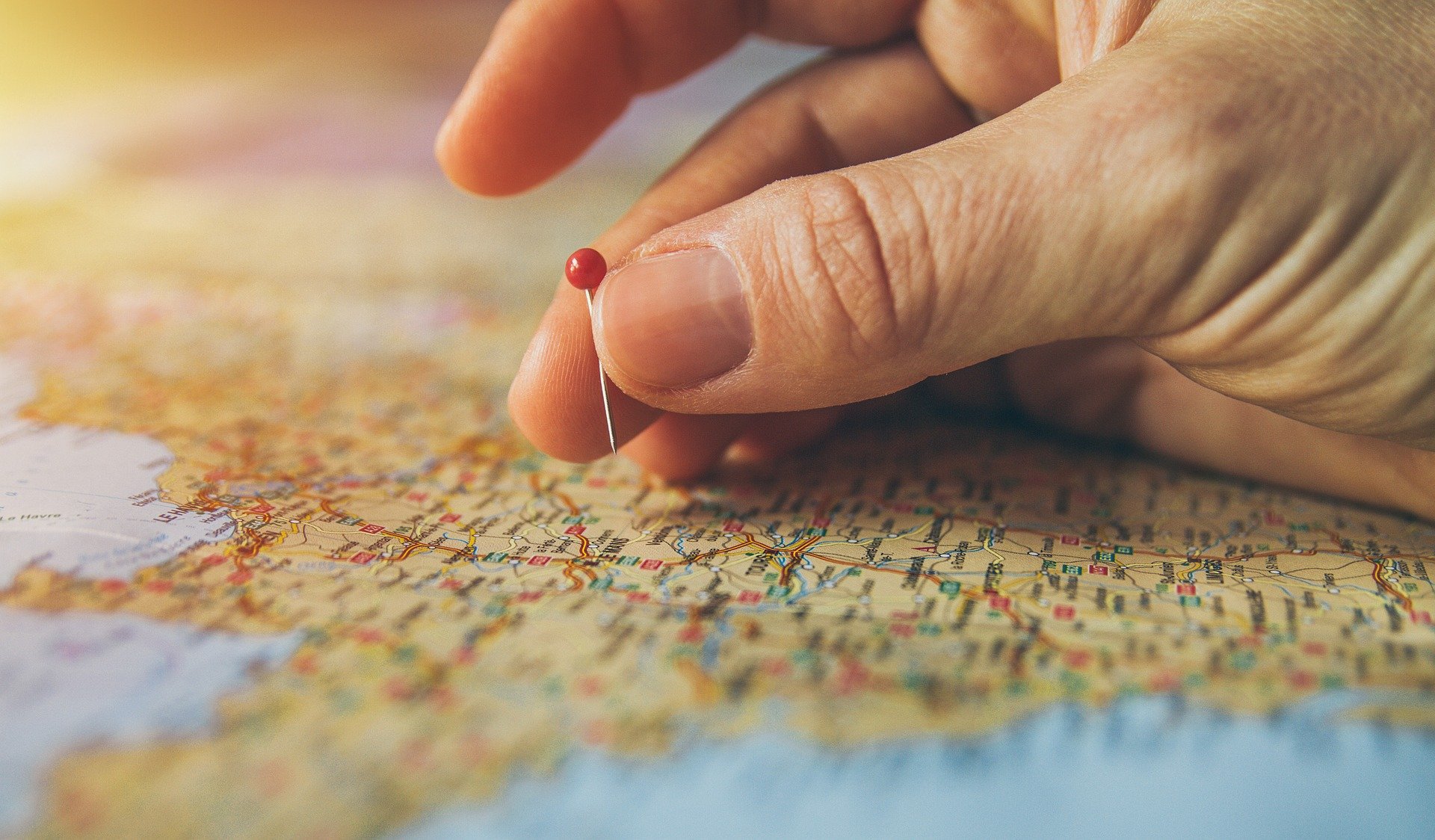 person putting pins into a map for travel destinations