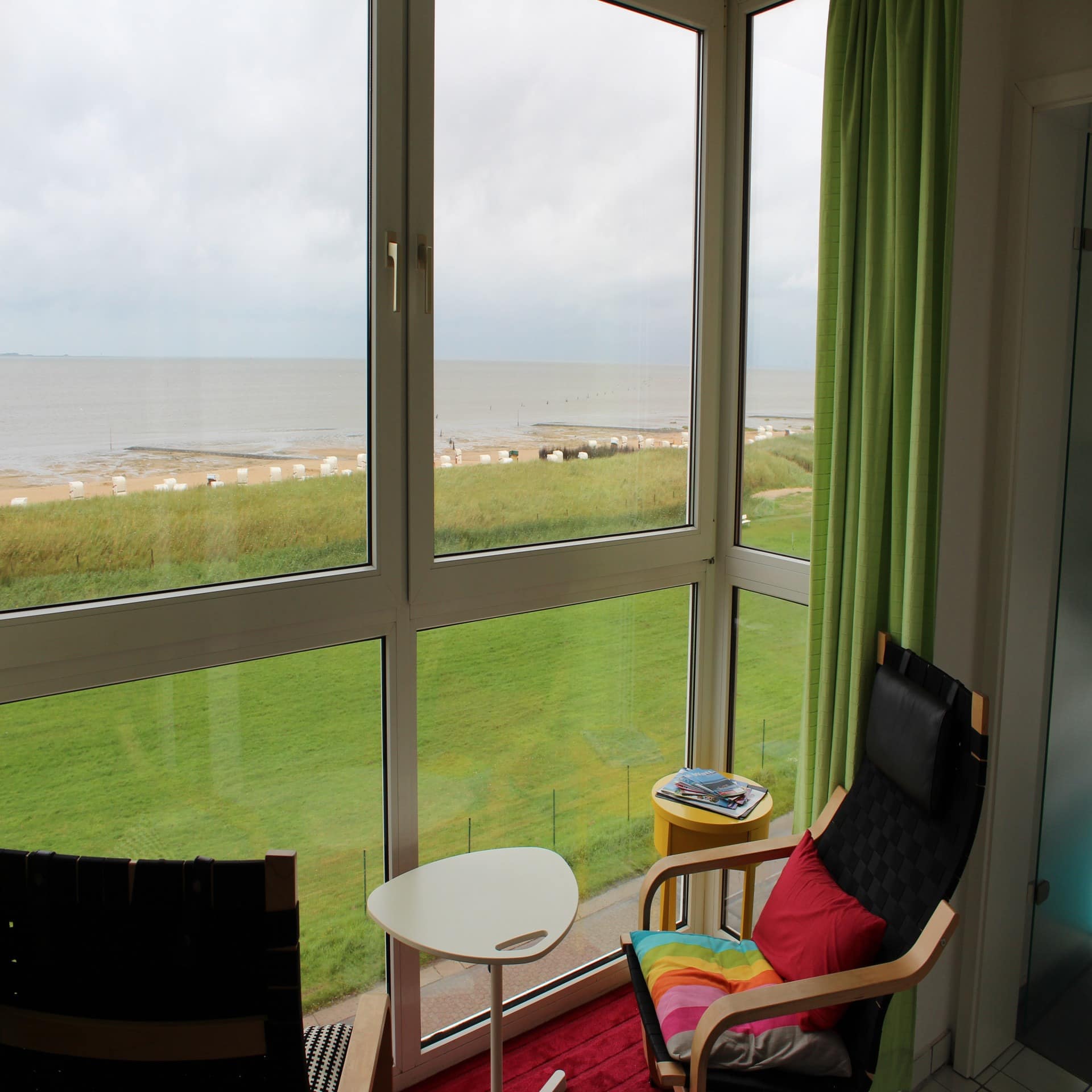 Blick vom Wintergarten über eine Wiese und den Strand von Duhnen. 