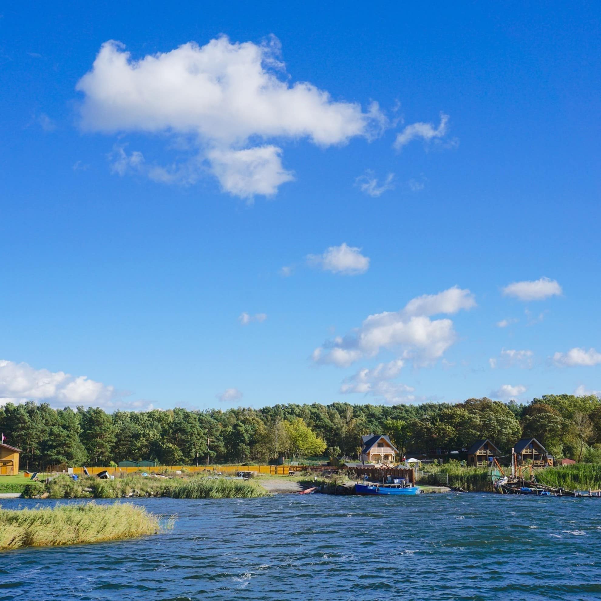 Blick vom Wasser der Mecklenburger Seenplatte auf Bungalows direkt am Ufer